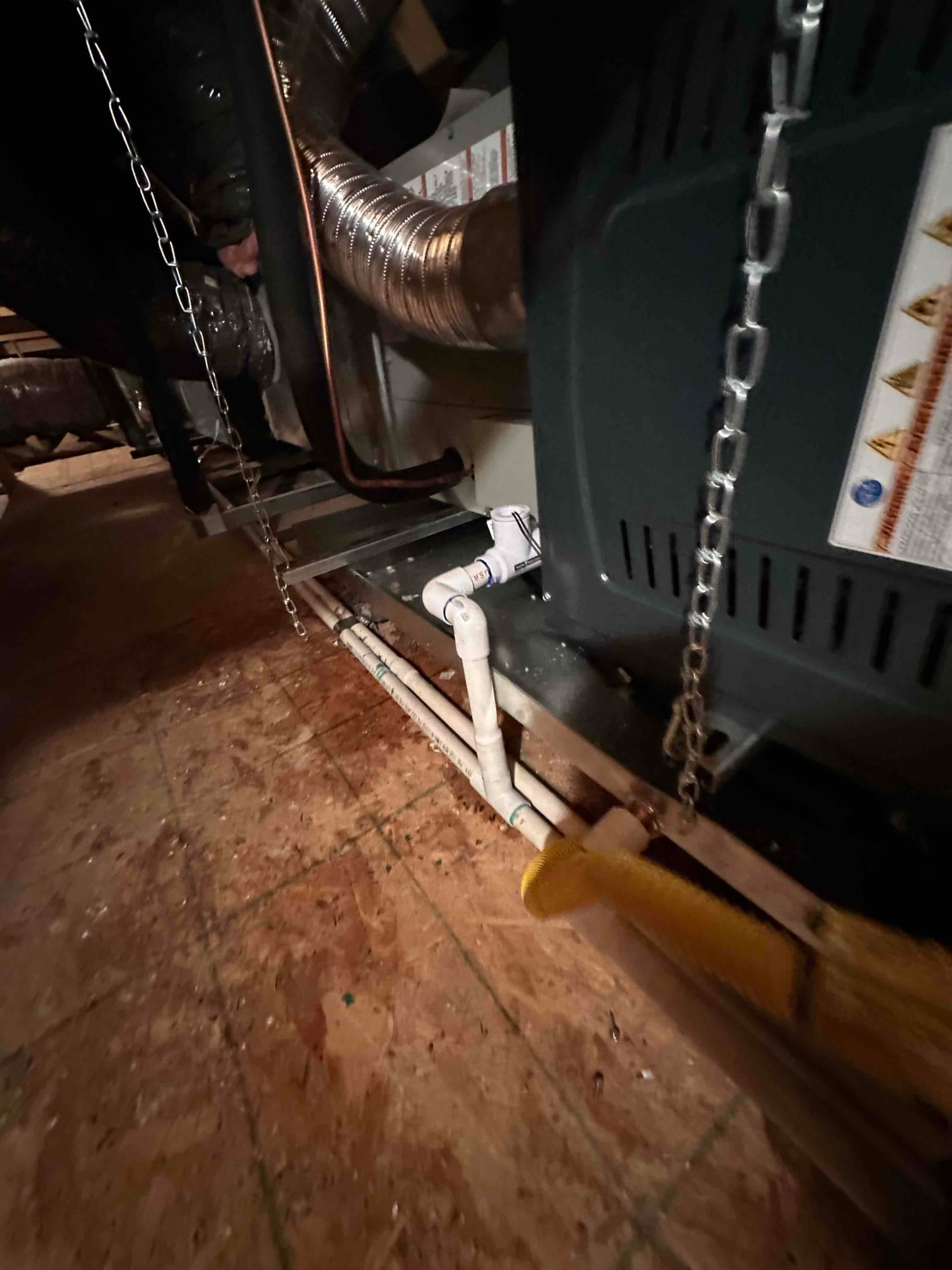 Attic air handler installation with insulated duct connection, copper refrigerant line, and PVC condensate drain piping routed along the platform.