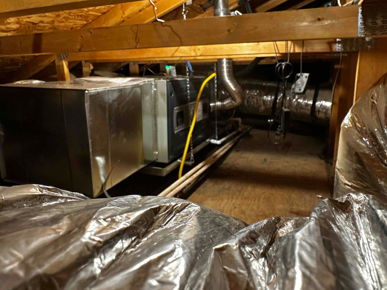 Attic-mounted air handler with new duct connections, insulated plenums, and condensate drain lines installed on a service platform.