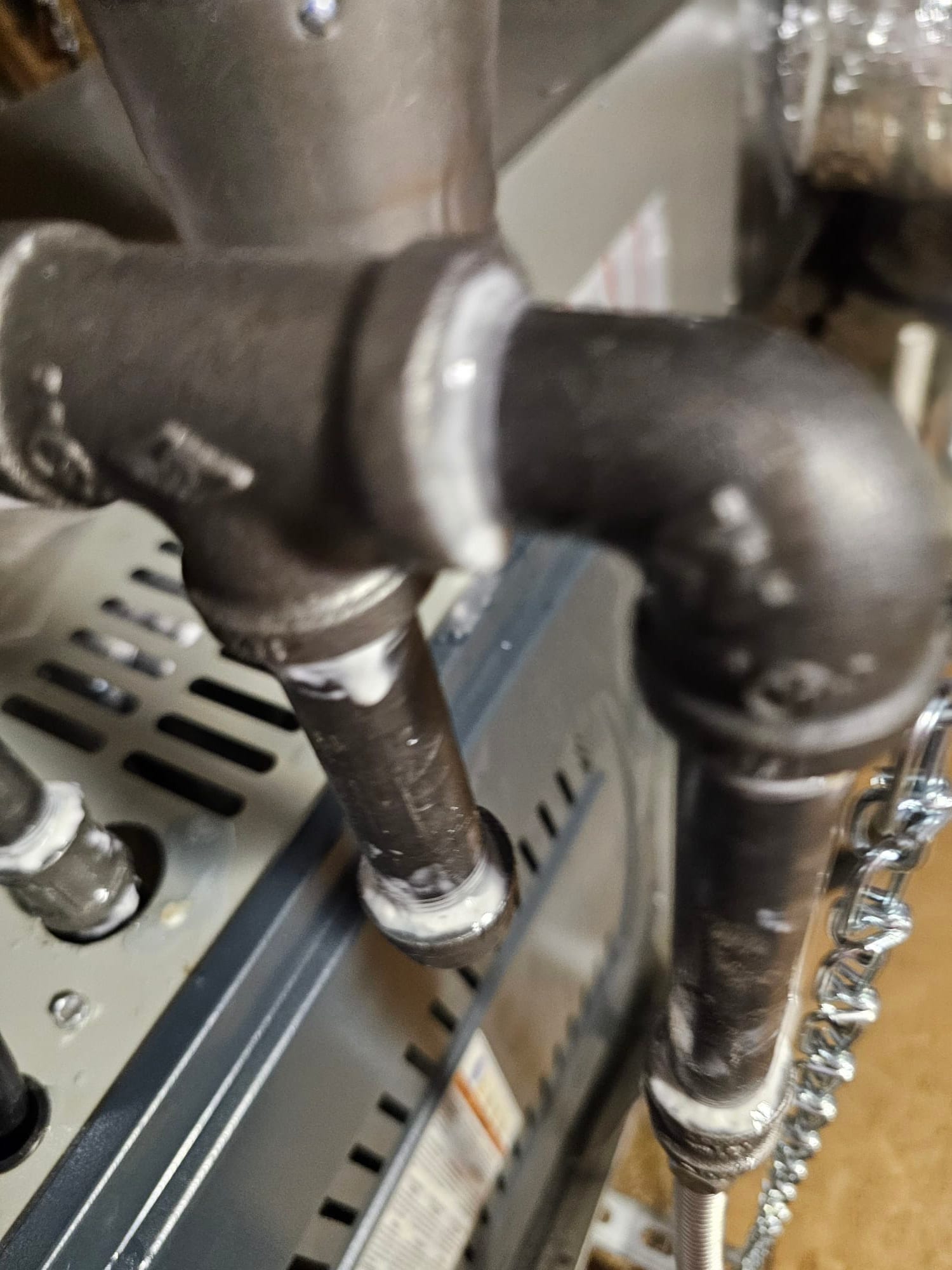 Black iron gas piping with threaded fittings and sealant connects to the furnace cabinet during installation.