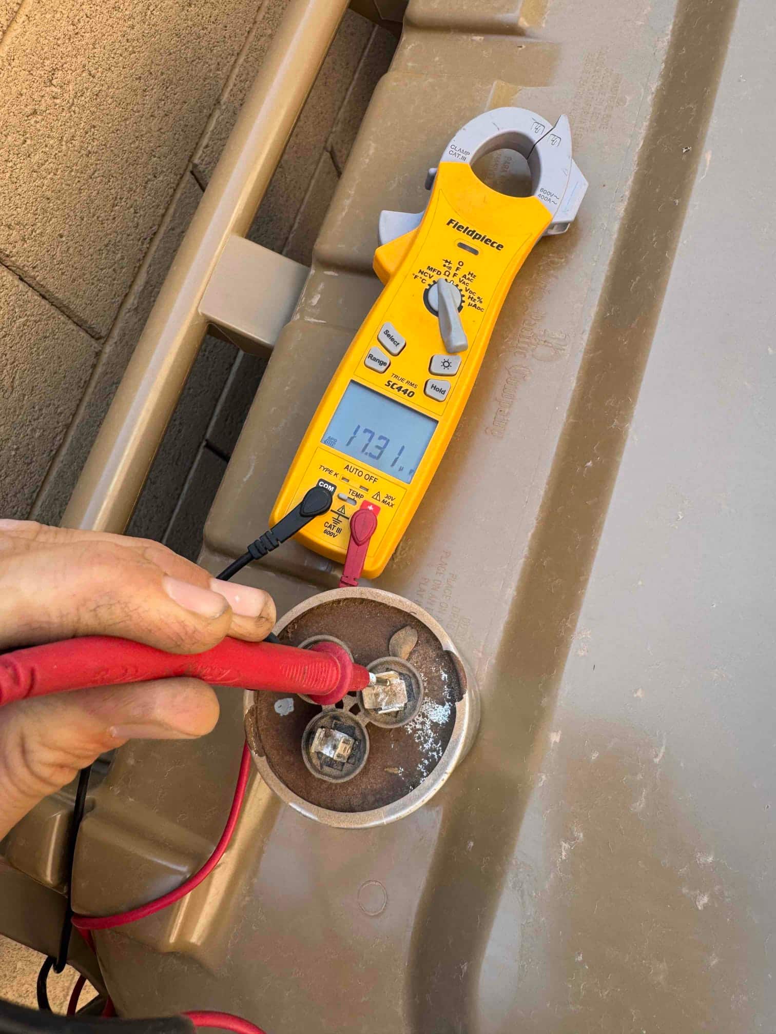 Clamp meter measures 17.31 μF on the capacitor terminals, with test leads connected to the component’s posts.