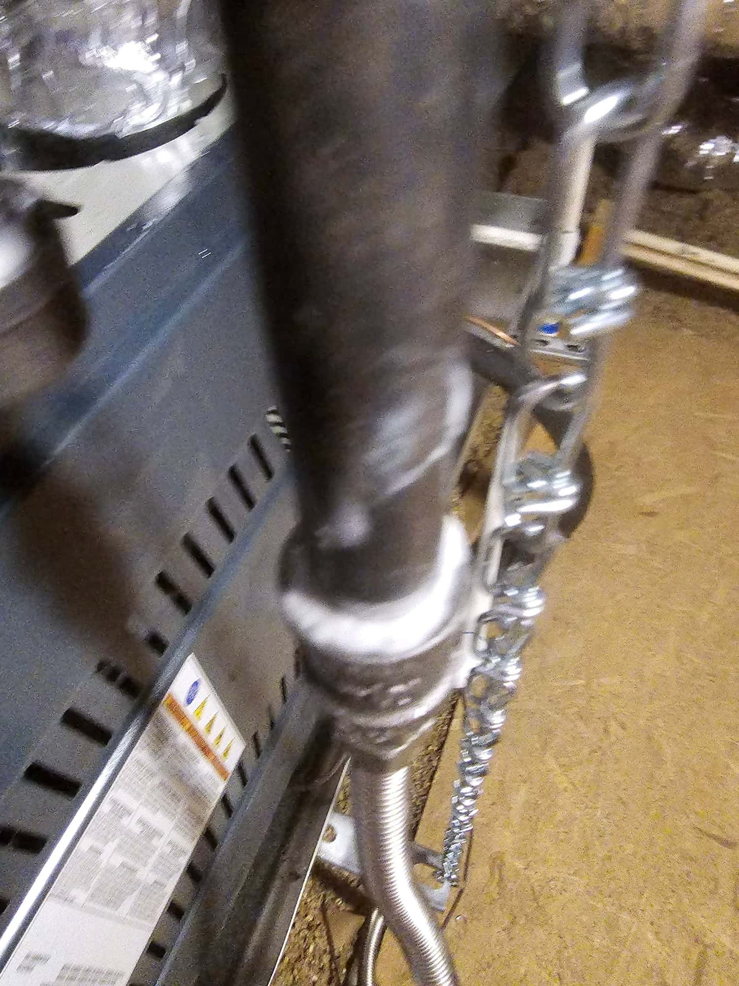 Close-up of a new furnace connection with flexible gas line, black iron pipe, and support chain in the mechanical area.