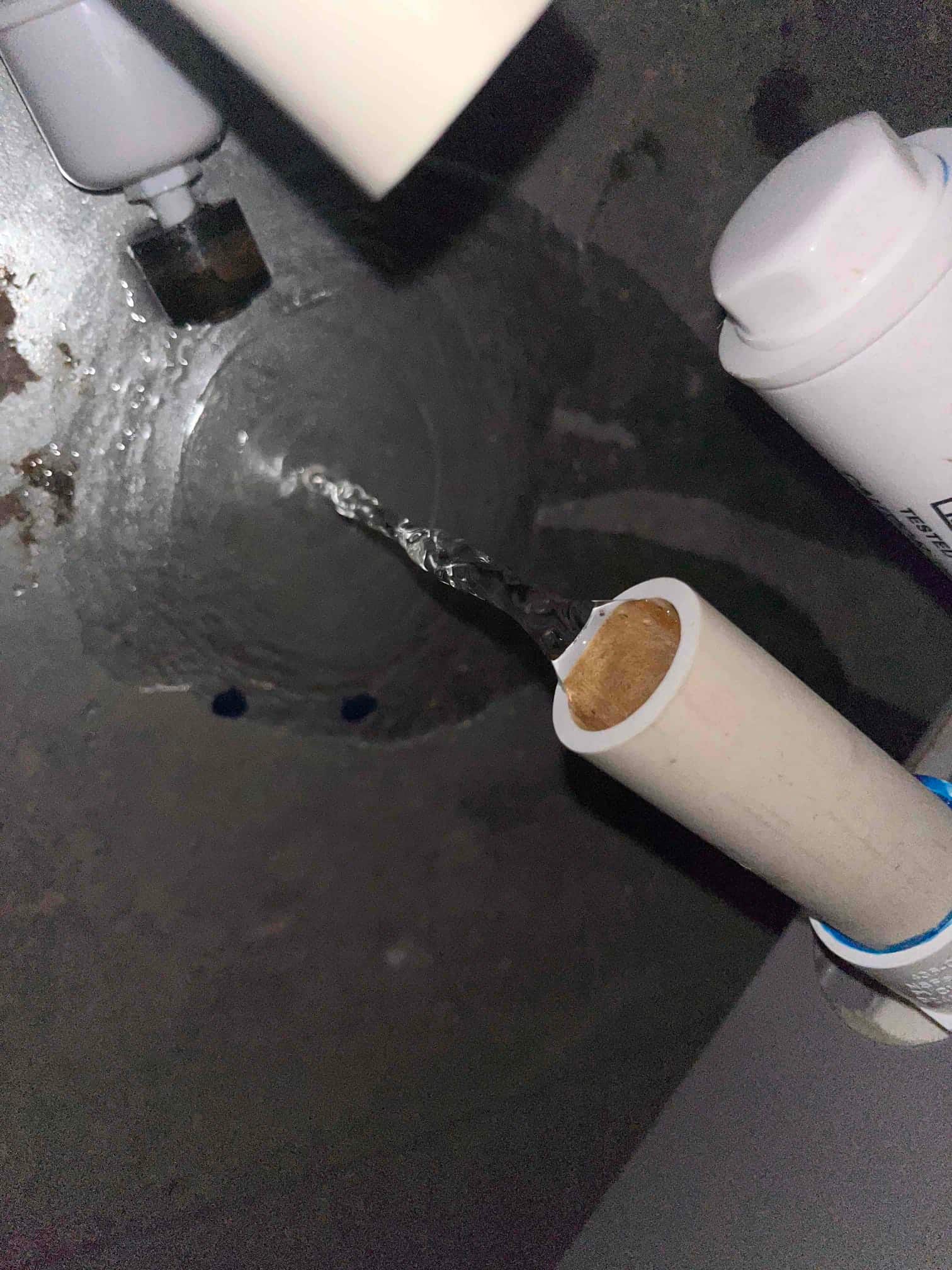 Condensate drain line discharging water into a drain pan area during air conditioning condensate line repair.