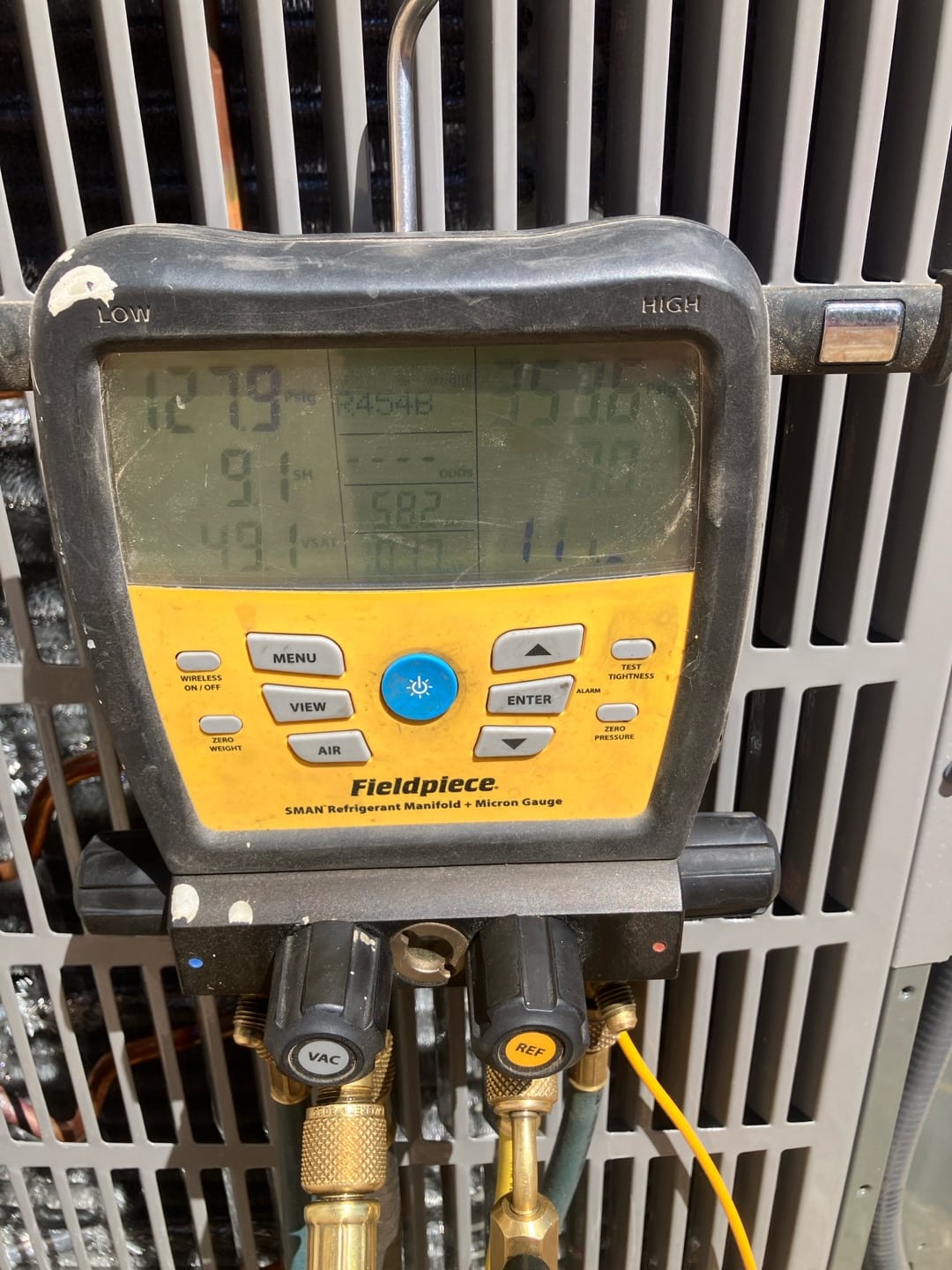 Digital manifold connected to the condenser shows operating refrigerant pressures with R-454B selected during system commissioning.