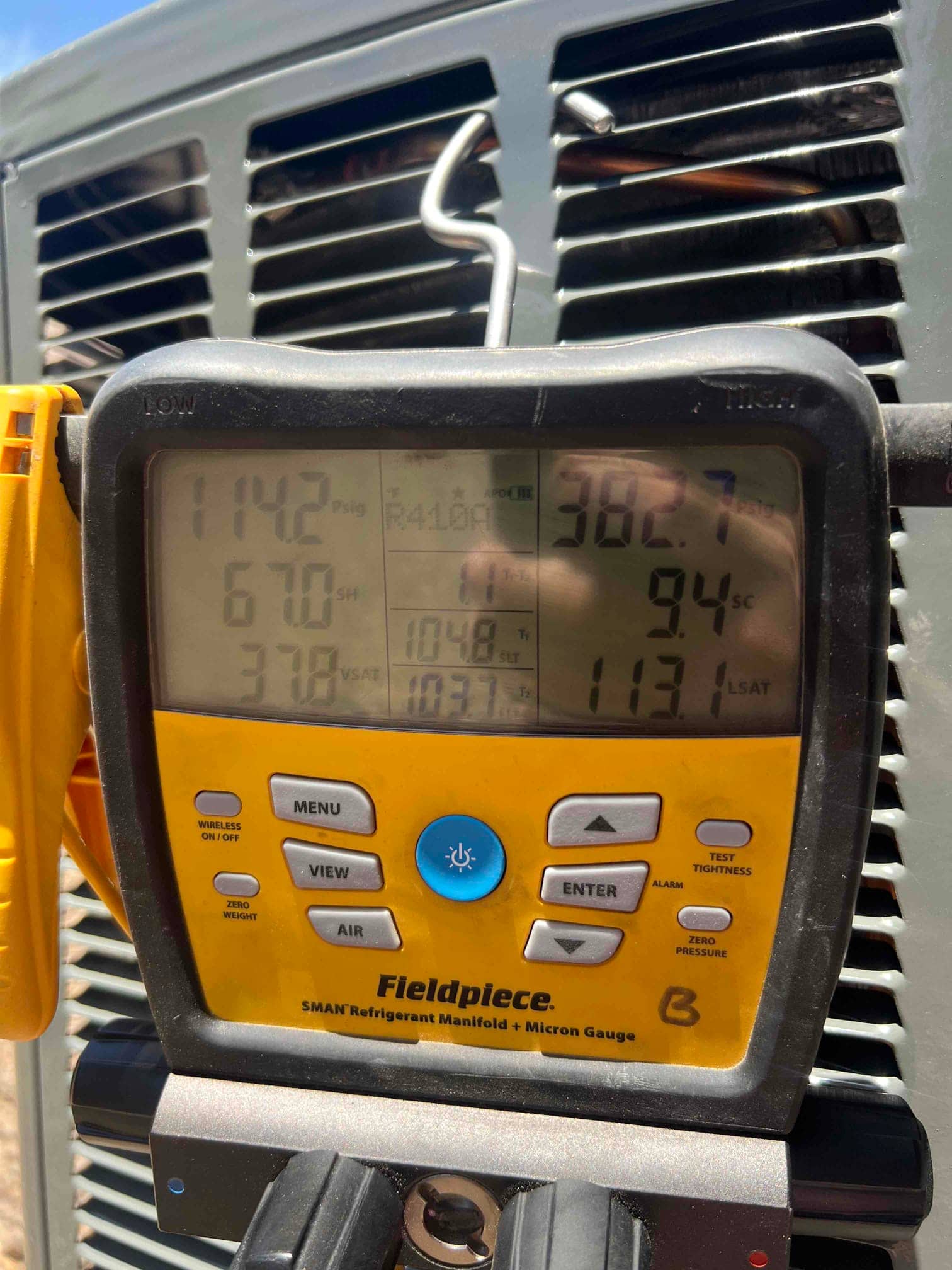 Digital manifold on the outdoor unit shows operating refrigerant pressures during system startup and charge verification.
