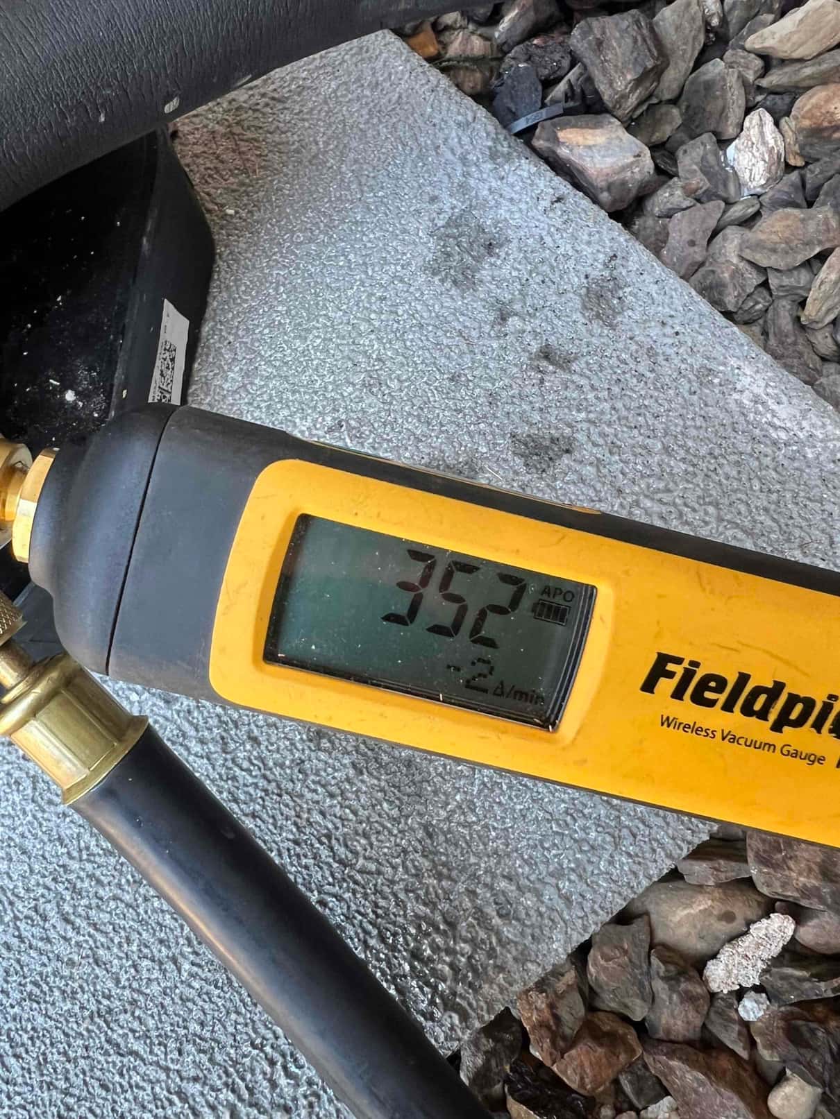 Digital micron gauge connected to the system shows 352 microns during evacuation, confirming a deep vacuum before refrigerant charging.