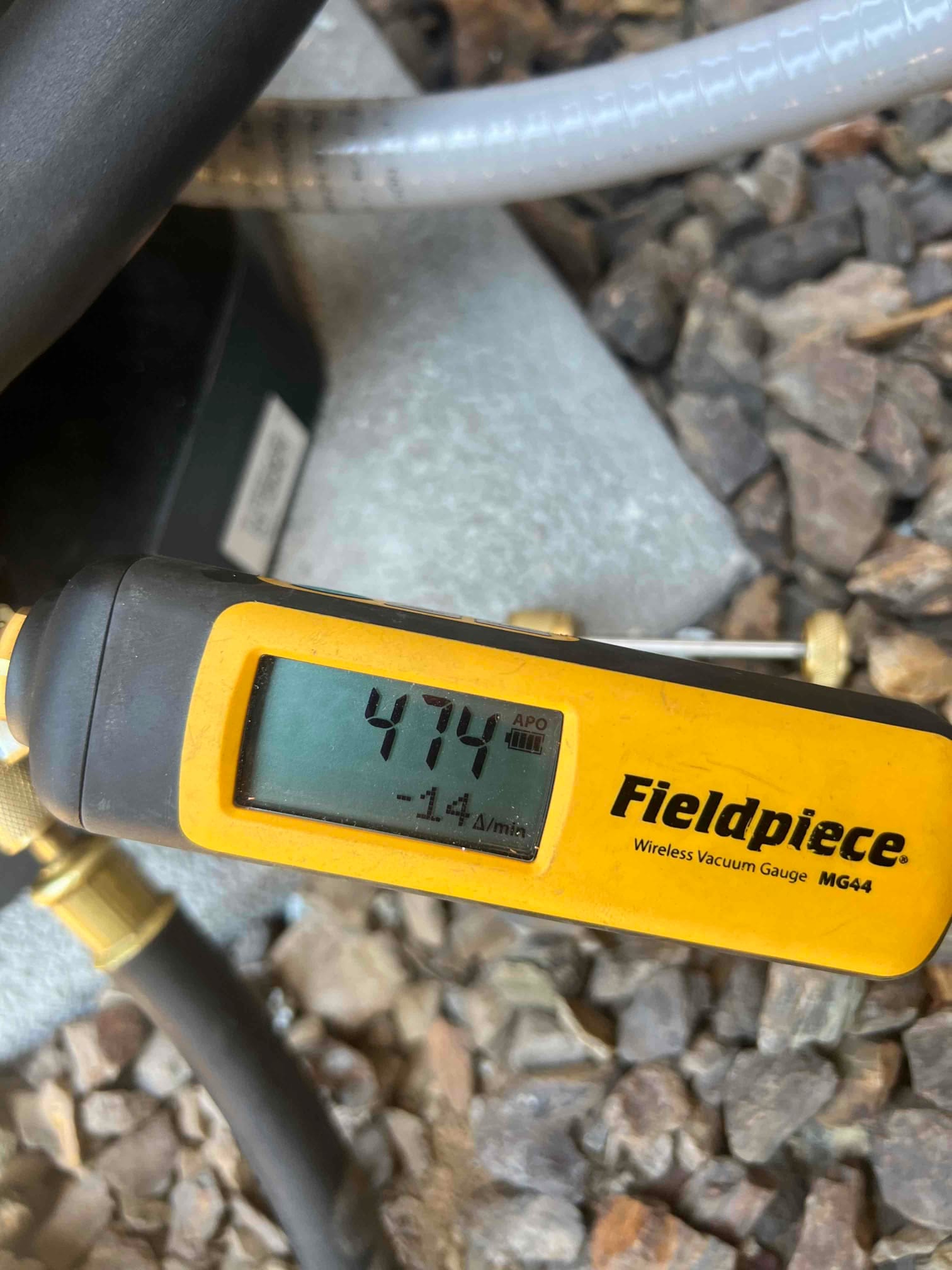 Digital micron gauge connected to the system shows 474 microns, confirming a deep vacuum during evacuation before refrigerant charging.