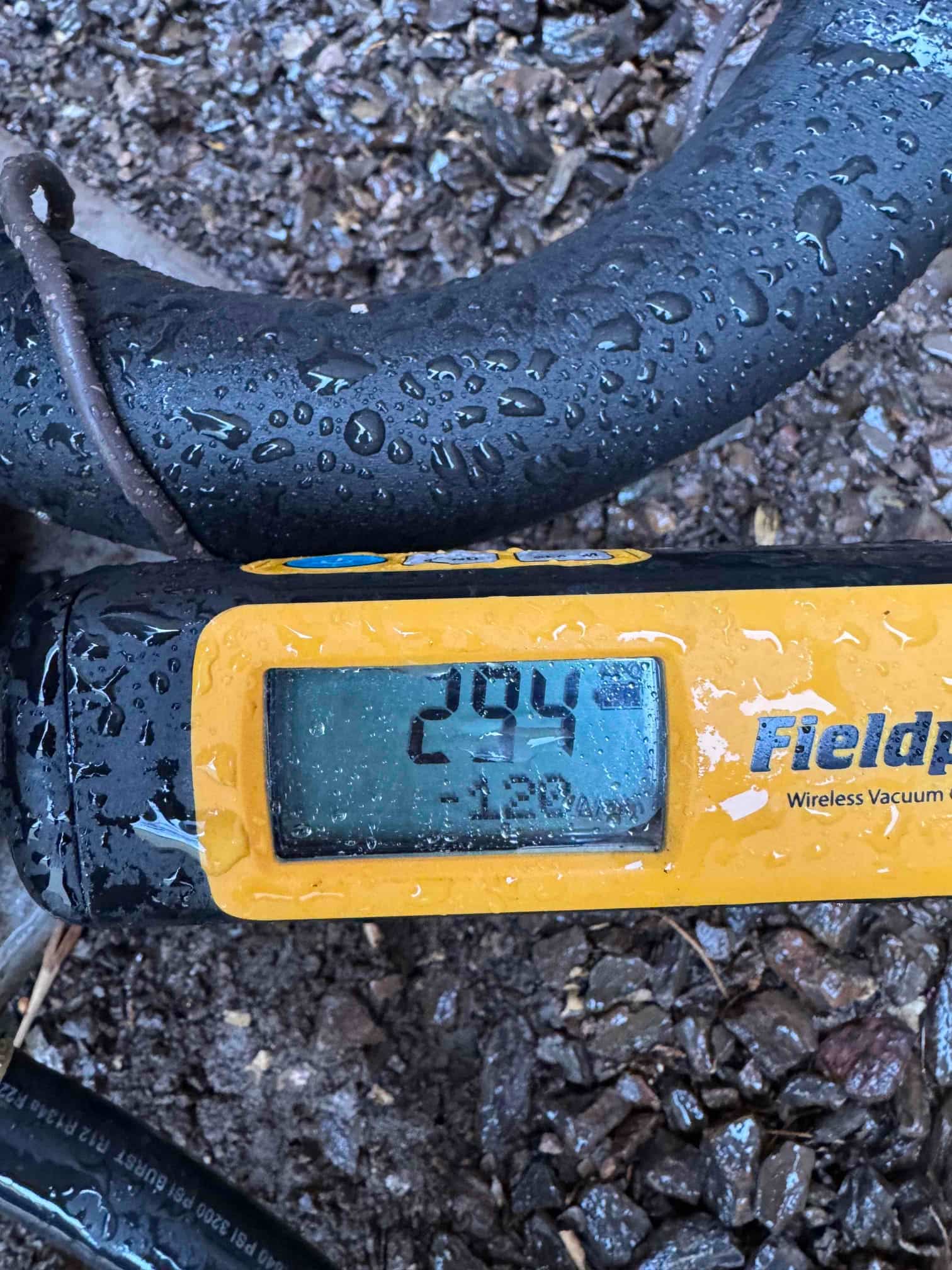 Digital micron gauge on the refrigerant line shows 294 microns during evacuation, confirming a deep vacuum before charging.