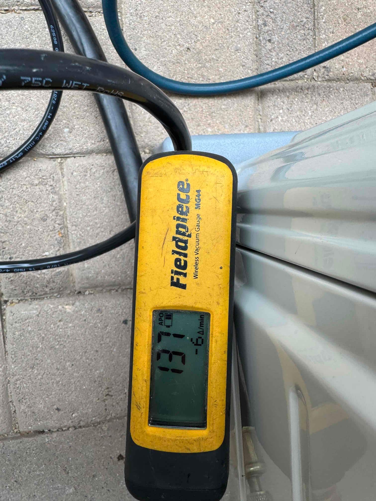 Digital micron gauge shows 137 microns, confirming a deep system evacuation before releasing refrigerant charge.