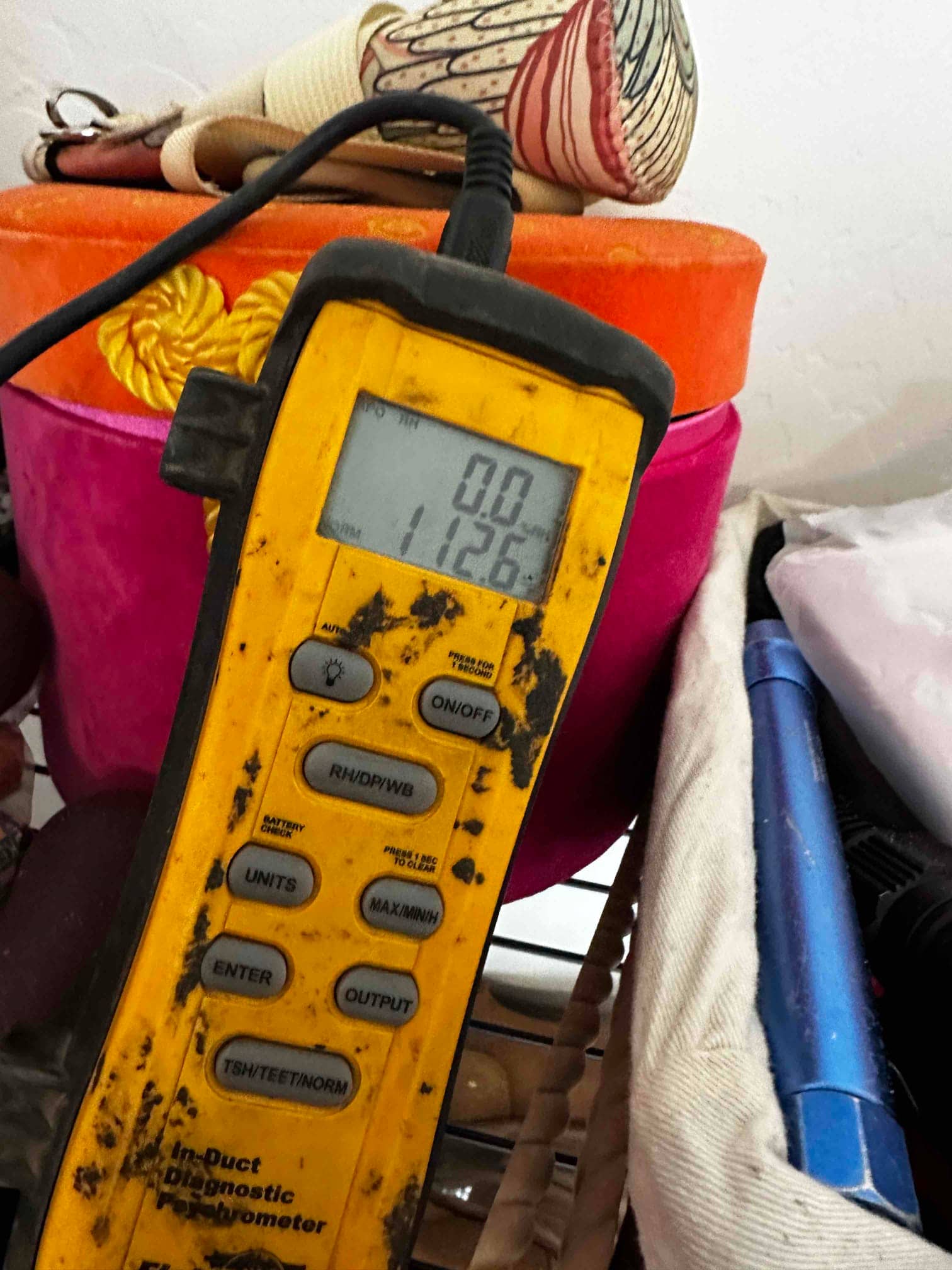 Digital probe thermometer/psychrometer in use during air-side commissioning; display shows 0.0 on the top line and 112.6 on the lower line.