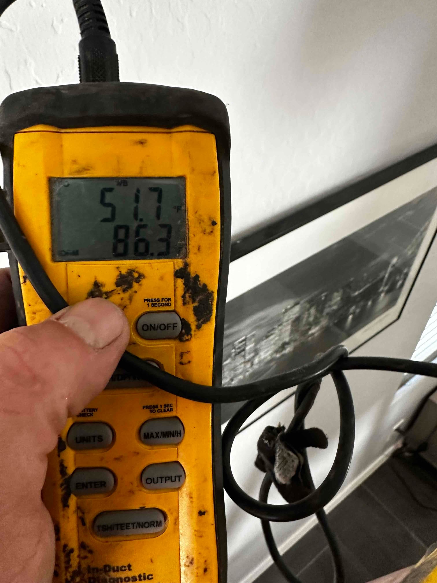 Digital thermometer displays 51.7°F, documenting cool supply air temperature during system commissioning.