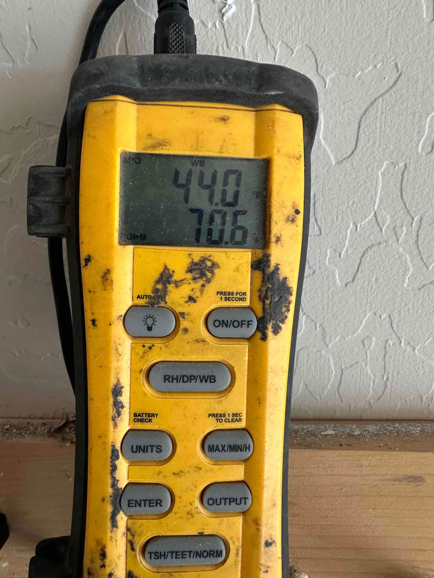 Digital thermometer displays 70.6 degrees, documenting return air temperature measurement during commissioning of the new system.
