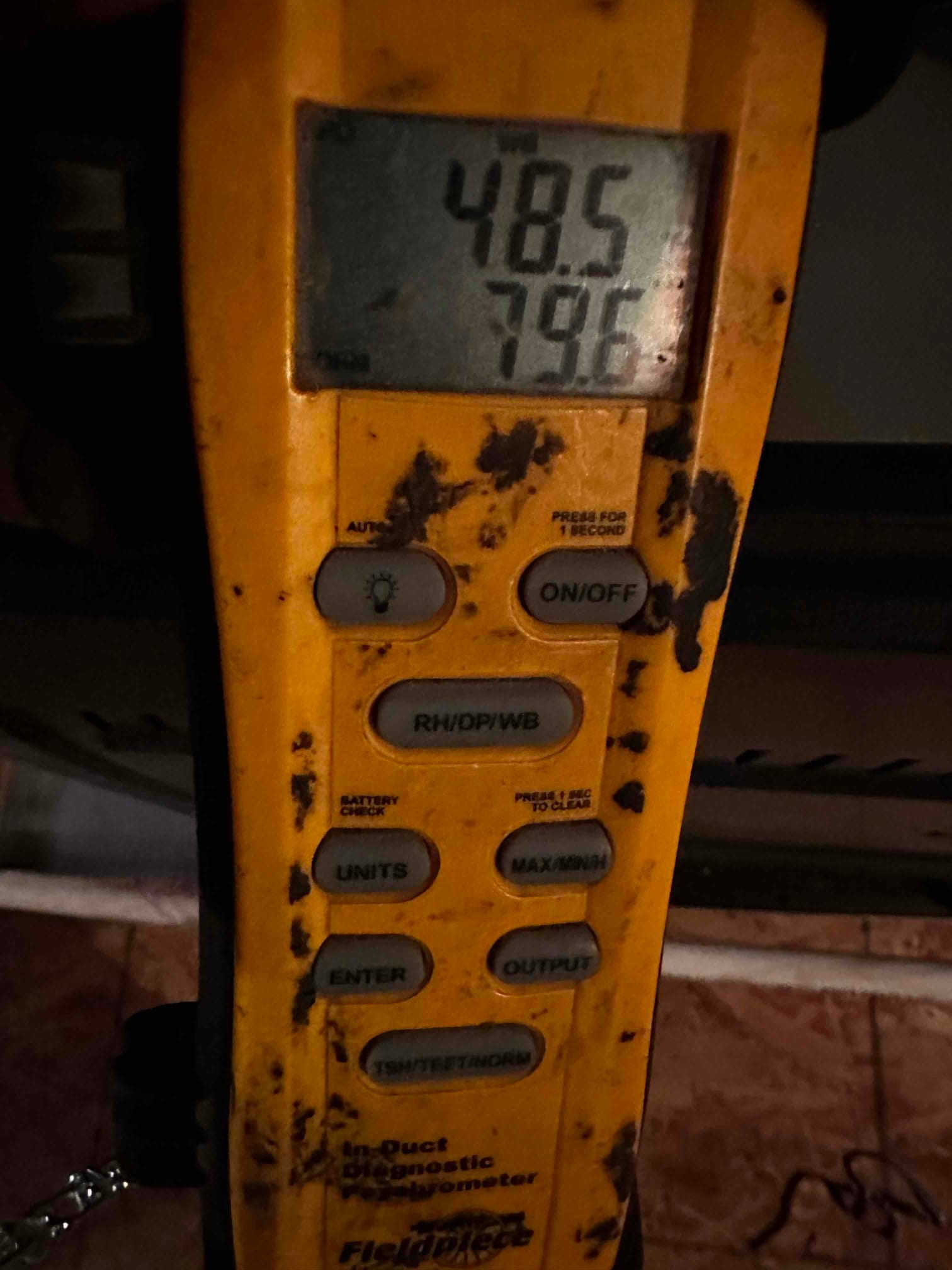 Digital thermometer shows 48.5 degrees, documenting cold supply air temperature during system commissioning.