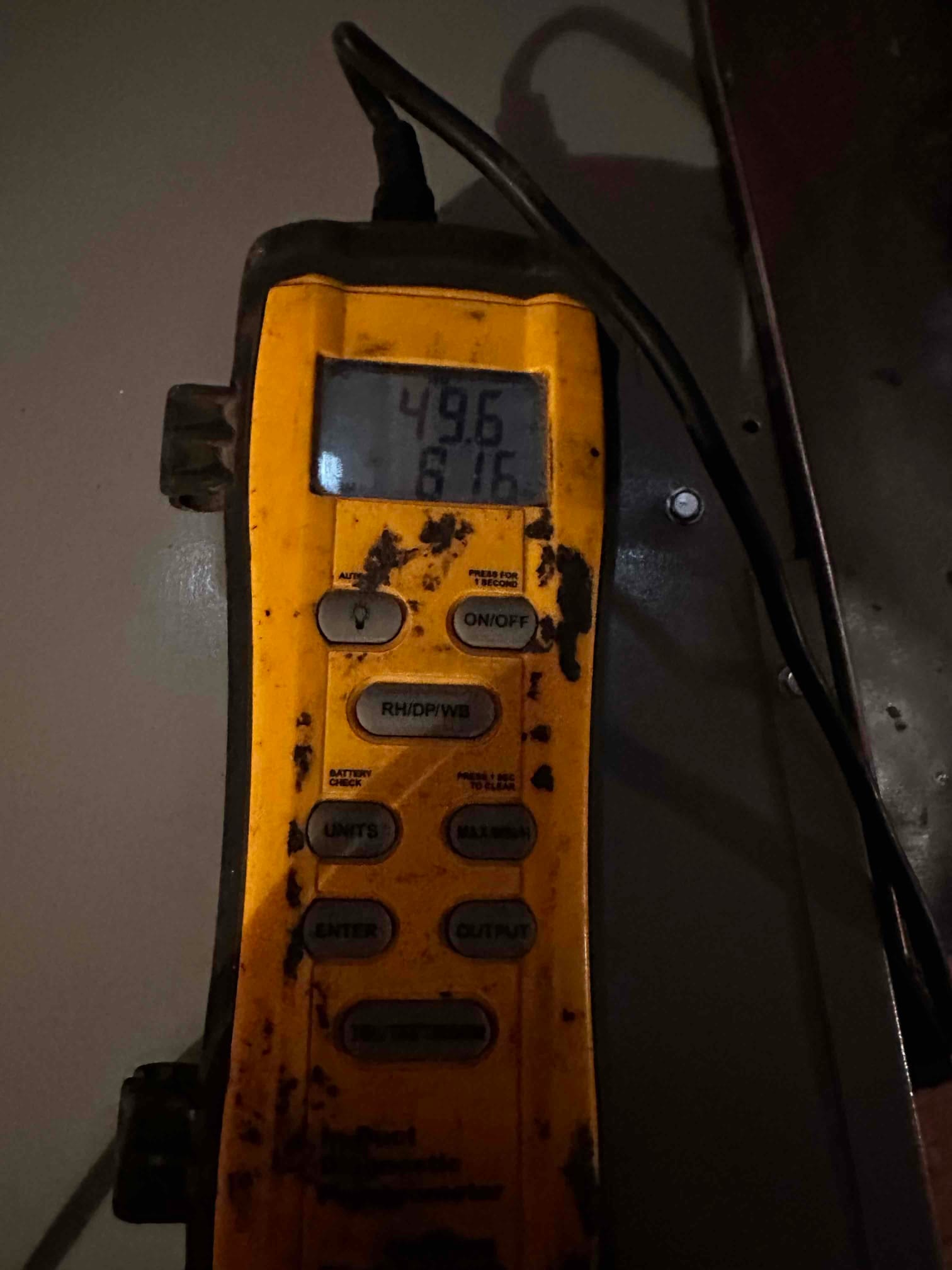 Digital thermometer shows a probe reading of 49.6 degrees Fahrenheit on the display during air temperature testing.