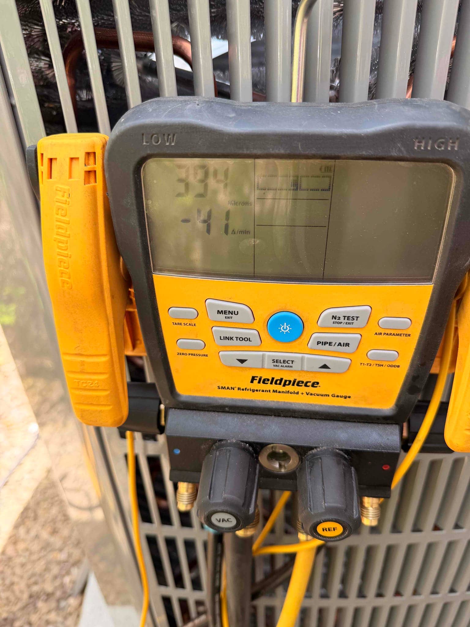 Digital vacuum gauge on the outdoor unit shows 394 microns during evacuation, confirming a deep vacuum before refrigerant charging.