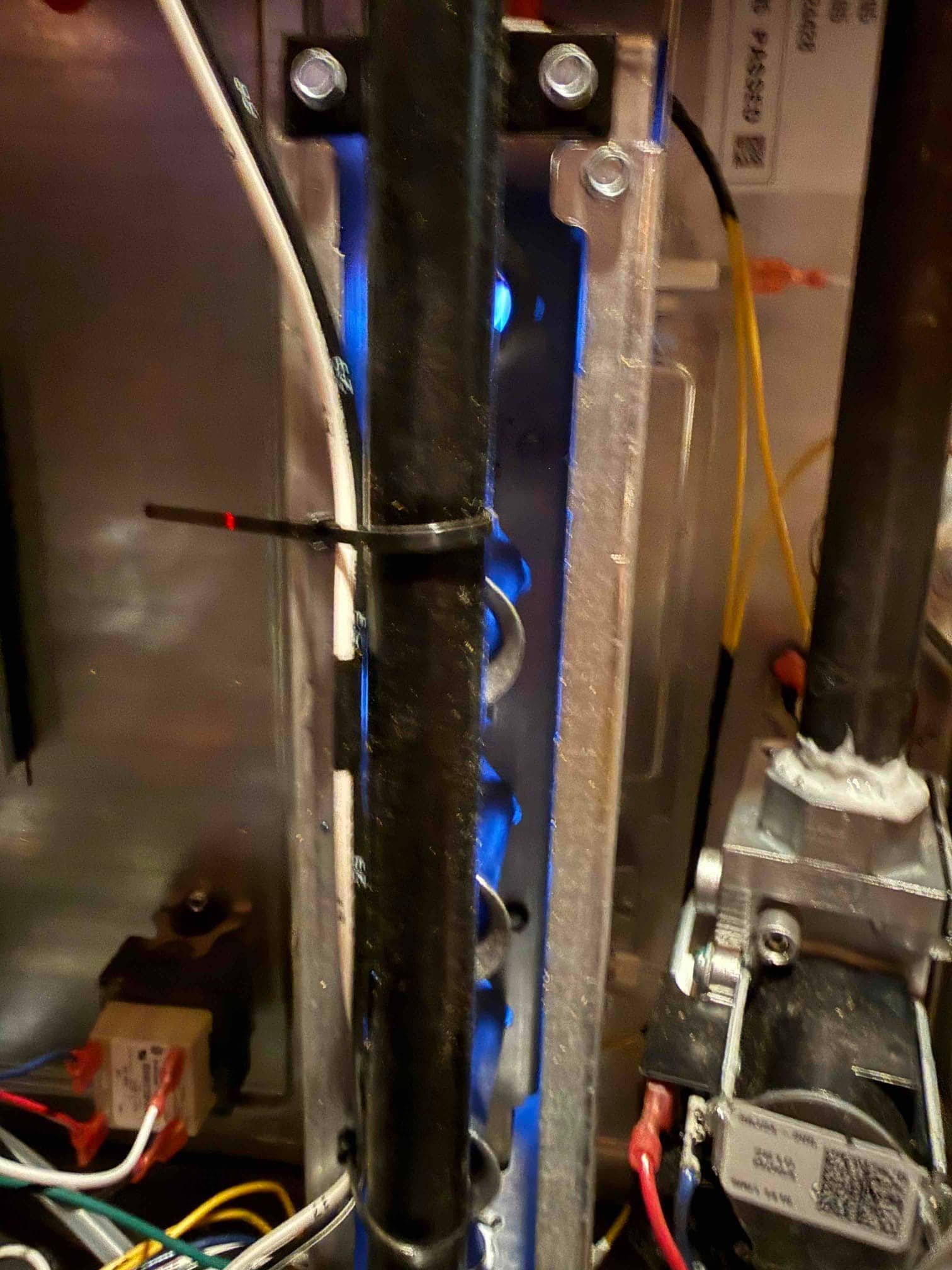 Gas furnace burners ignite with steady blue flames during startup, with gas valve, wiring, and manifold visible.