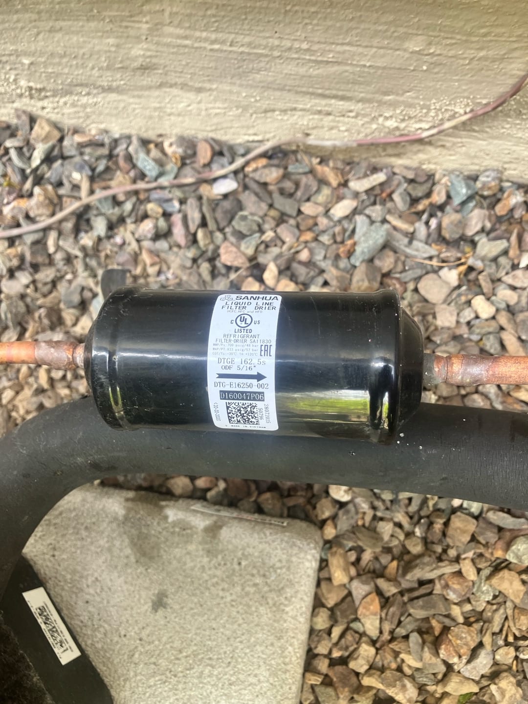 Liquid-line filter drier brazed into the refrigerant line outside, showing proper installation with insulated suction line nearby.