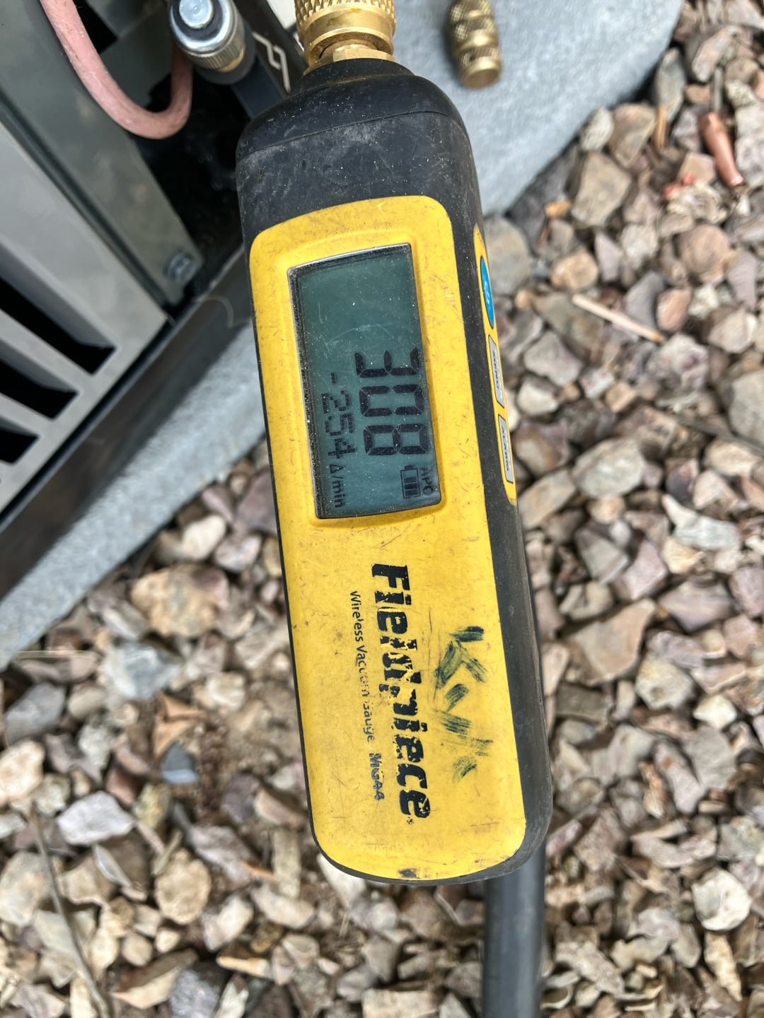 Micron gauge connected at the outdoor unit reads 308 microns, confirming a deep vacuum during system evacuation.