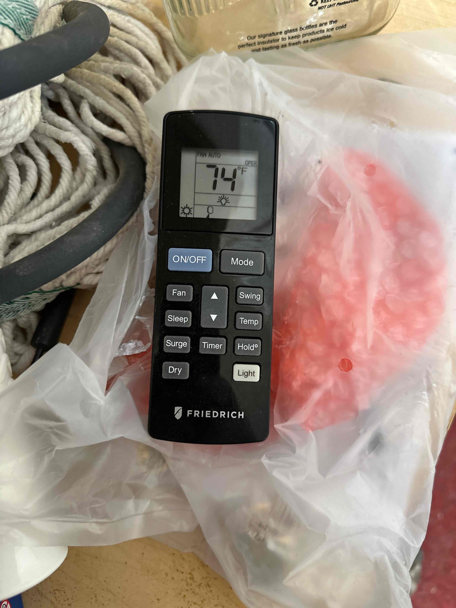 Mini-split handheld remote control displays a set temperature of 74°F with fan on auto mode.