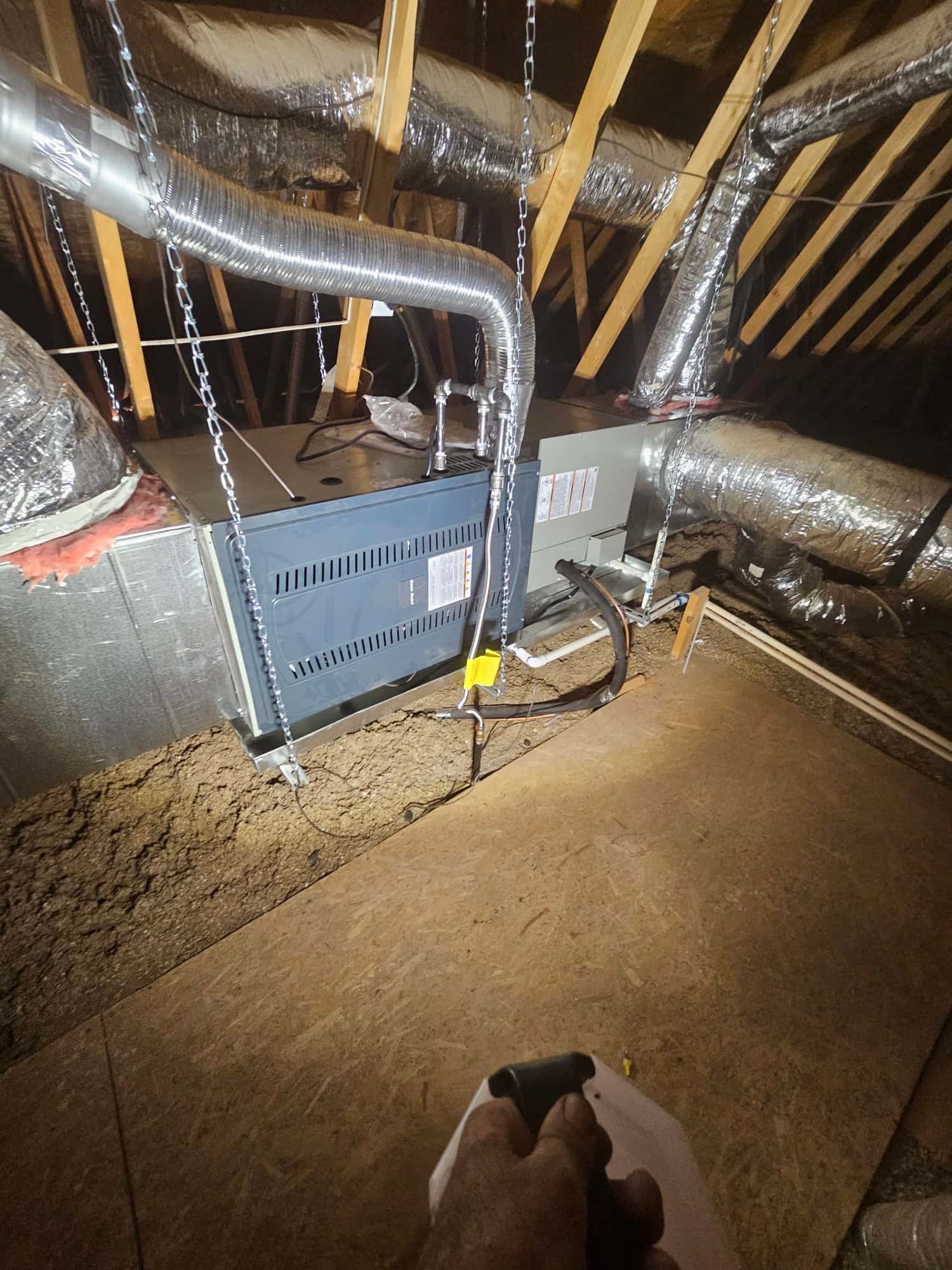 New attic air handler and duct connections suspended with chains, insulated flex ducts attached, condensate drain and refrigerant lines routed cleanly.