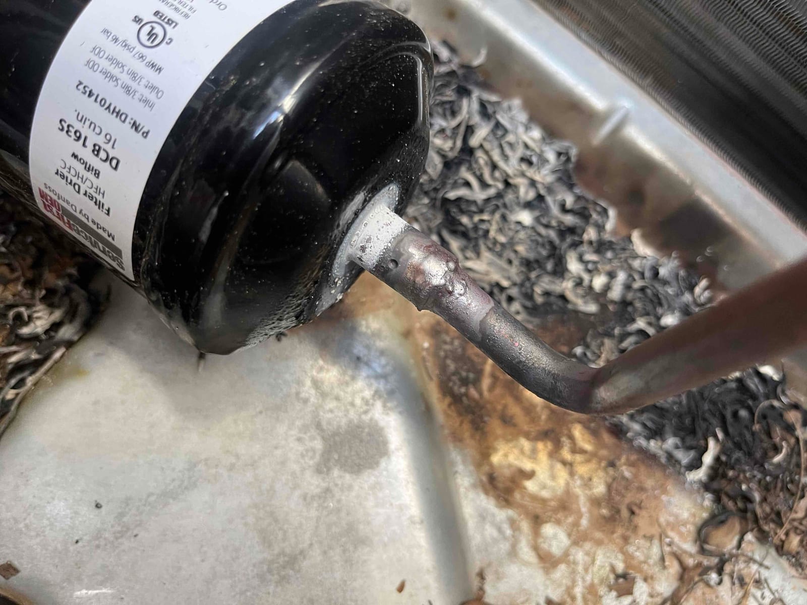 New filter drier installed in the condenser, showing freshly brazed copper connections and clean surrounding pan area.