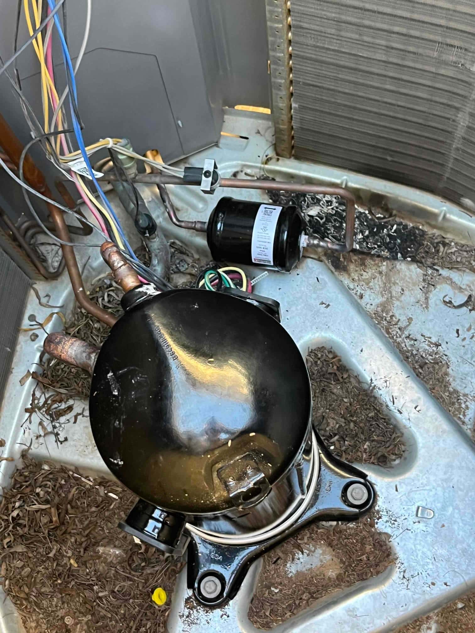 New hermetic compressor set in the condenser base with copper stub-outs exposed, and a new filter drier positioned nearby.