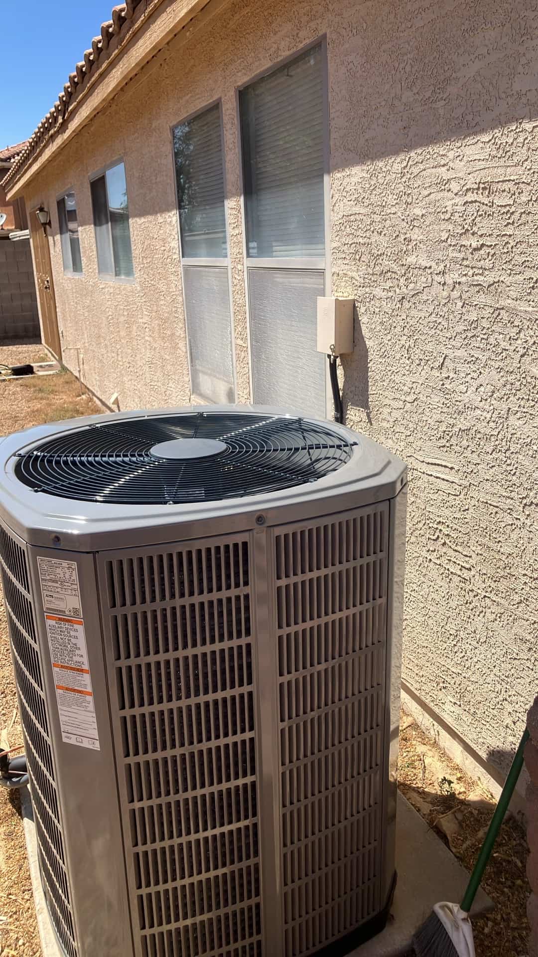 New outdoor condenser set on a level pad beside the house with disconnect box mounted and line set routed.