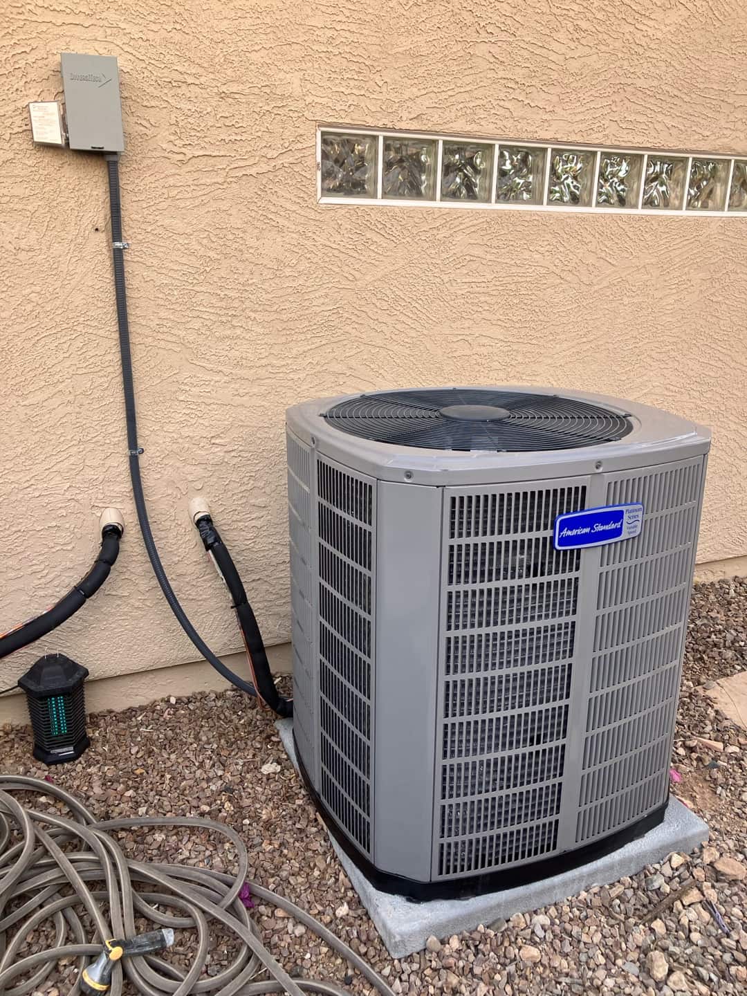 New outdoor condenser set on a level pad with insulated refrigerant lines and weatherproof disconnect installed on the exterior wall.