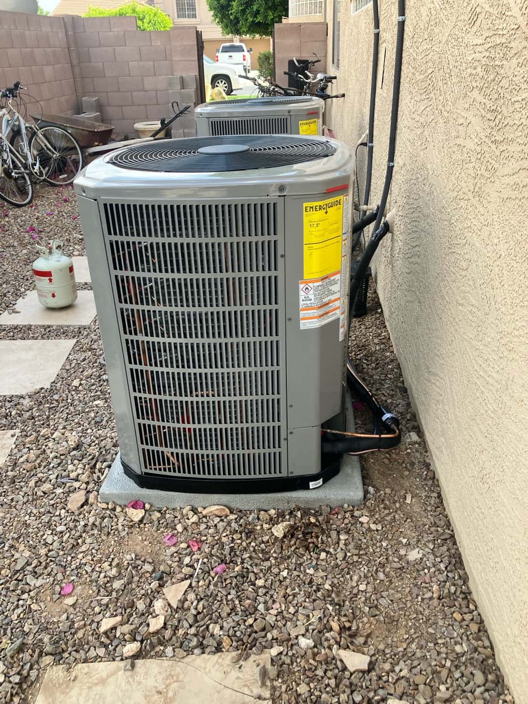 Two new outdoor condensers set on level pads with insulated line sets routed along the exterior wall.