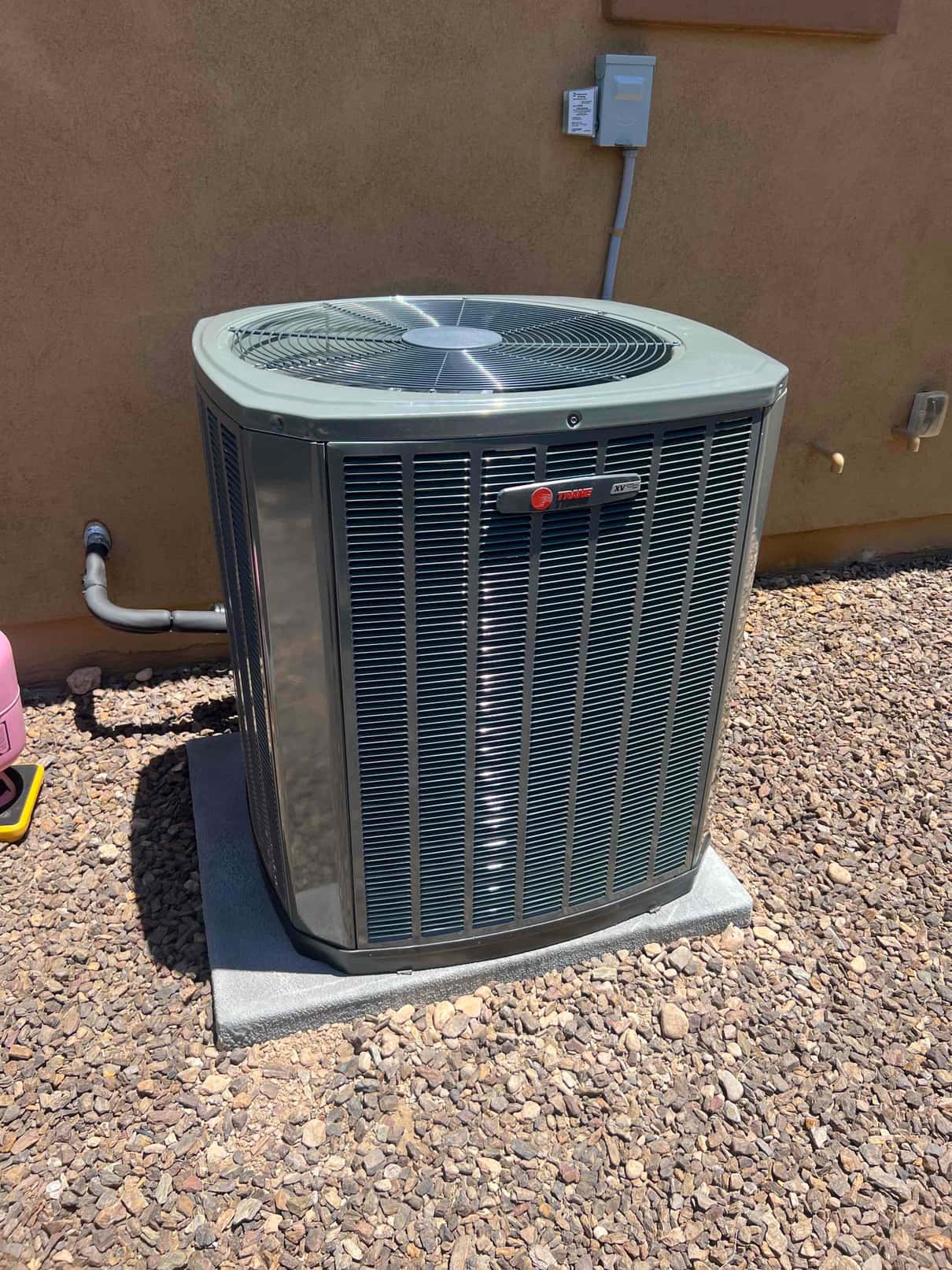 New outdoor condensing unit set on a level pad with sealed line set penetration and mounted electrical disconnect.