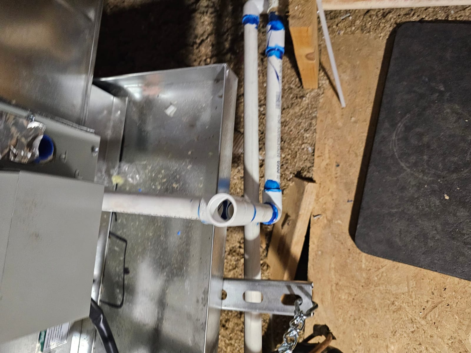 New PVC condensate drain assembly with cleanout and glued fittings connected to the air handler in the crawlspace.