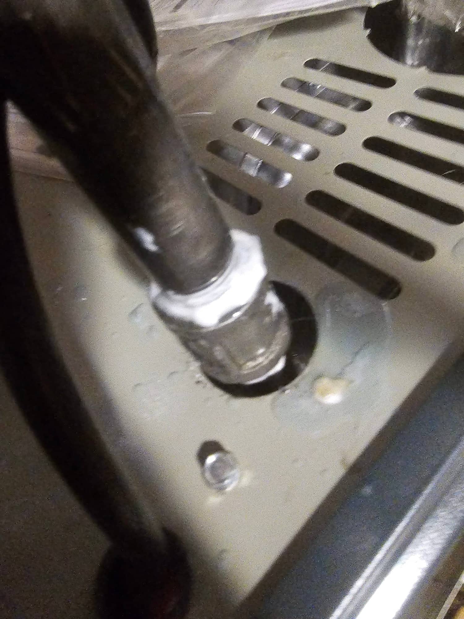 Refrigerant line penetration sealed with mastic at the air handler cabinet, showing clean routing through the metal base.