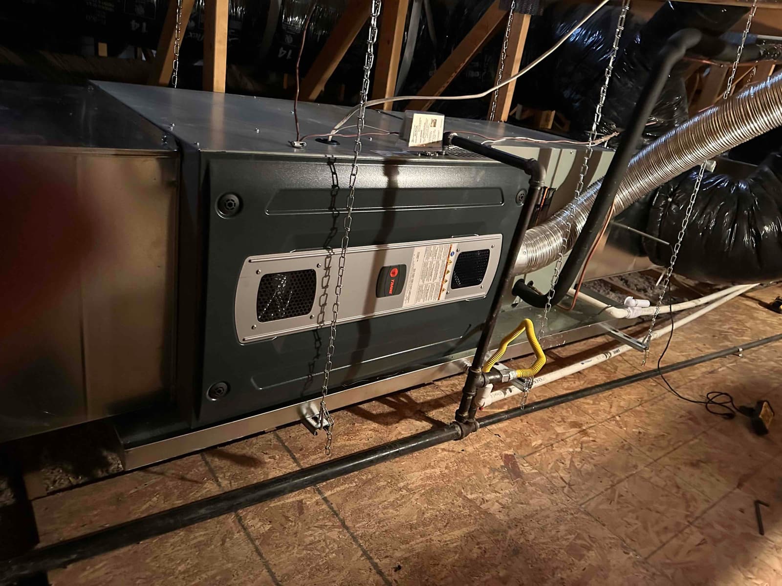 Suspended furnace and evaporator assembly installed in attic with gas line, condensate drain, and insulated duct connections secured.