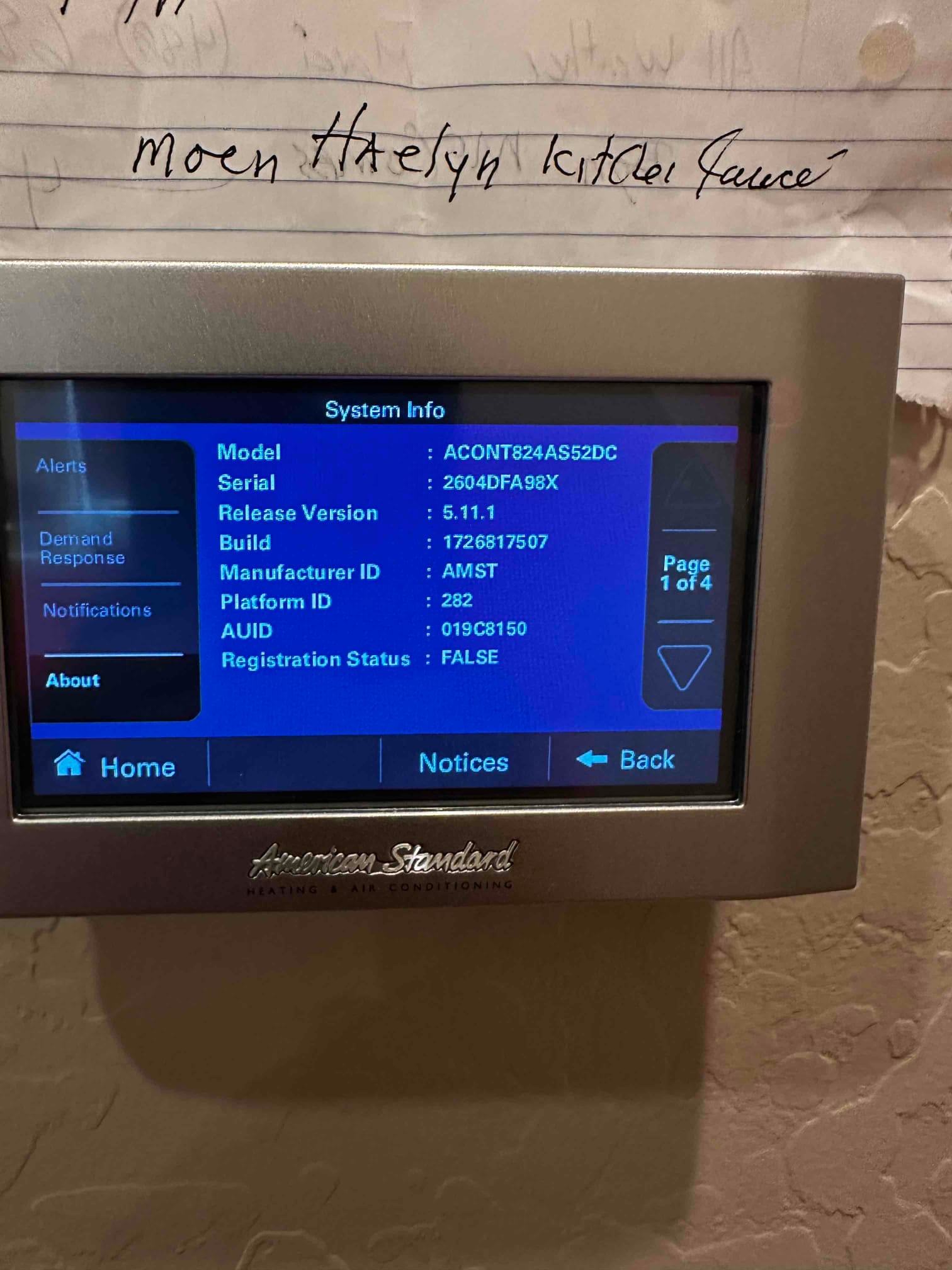 Touchscreen HVAC thermostat displaying system information on the wall after installation, with menu options visible on the screen.