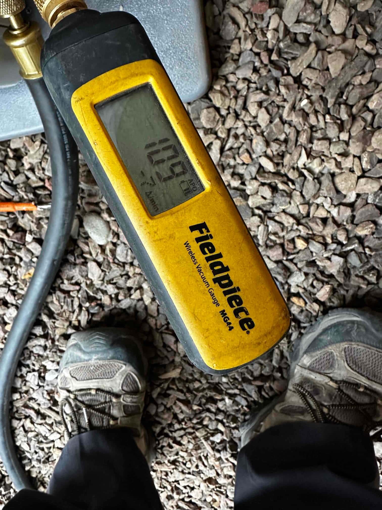 Wireless micron gauge connected during evacuation reads 109 microns, confirming a deep vacuum before refrigerant charging.