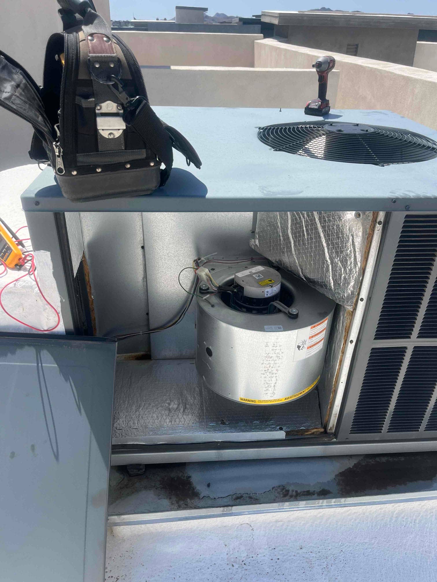 Air handler cabinet open on rooftop unit showing newly installed indoor blower motor assembly with wiring and insulation visible.