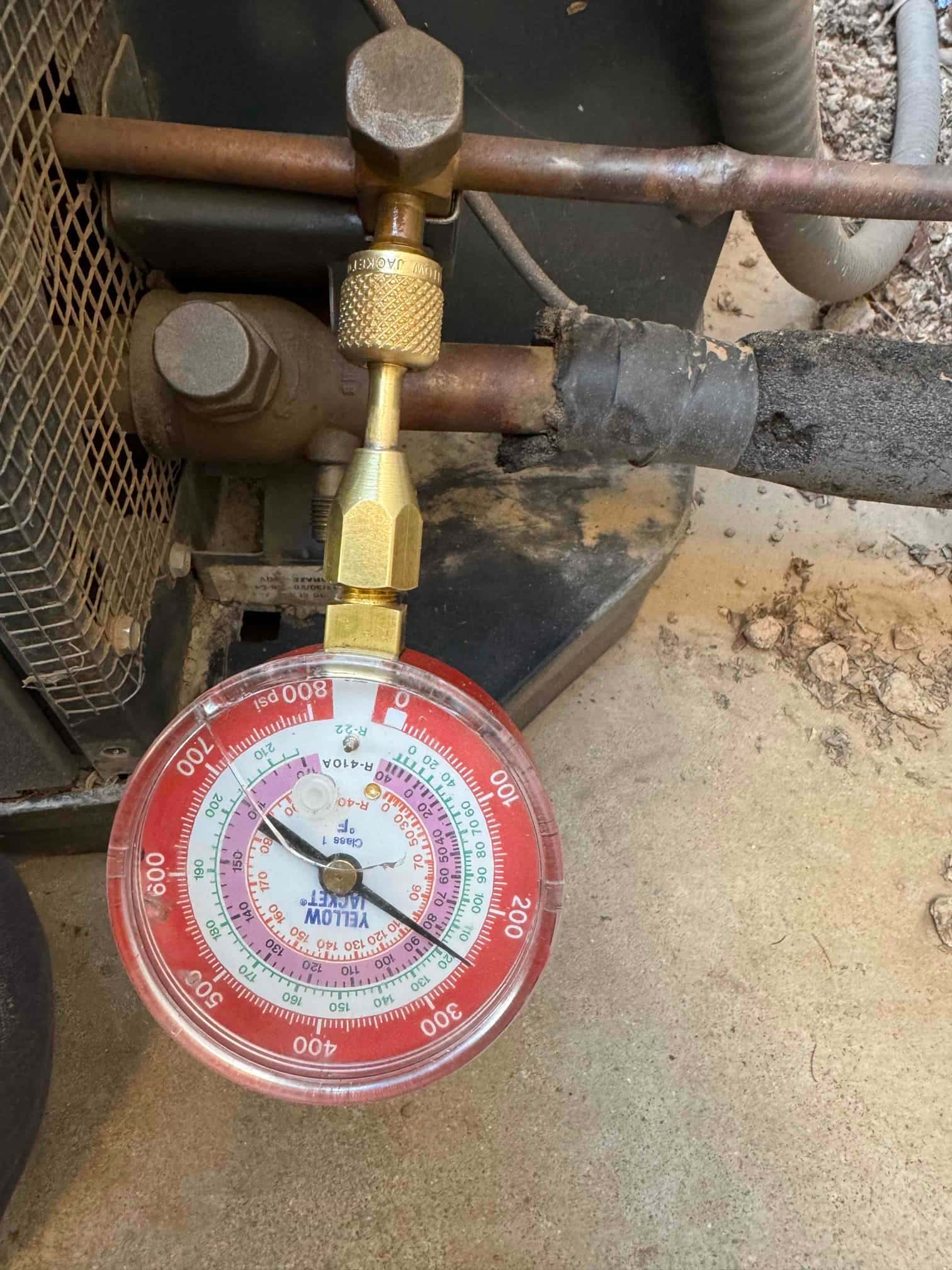 Analog refrigerant gauge connected to the suction service port shows approximately 85 psi low-side pressure during system check.