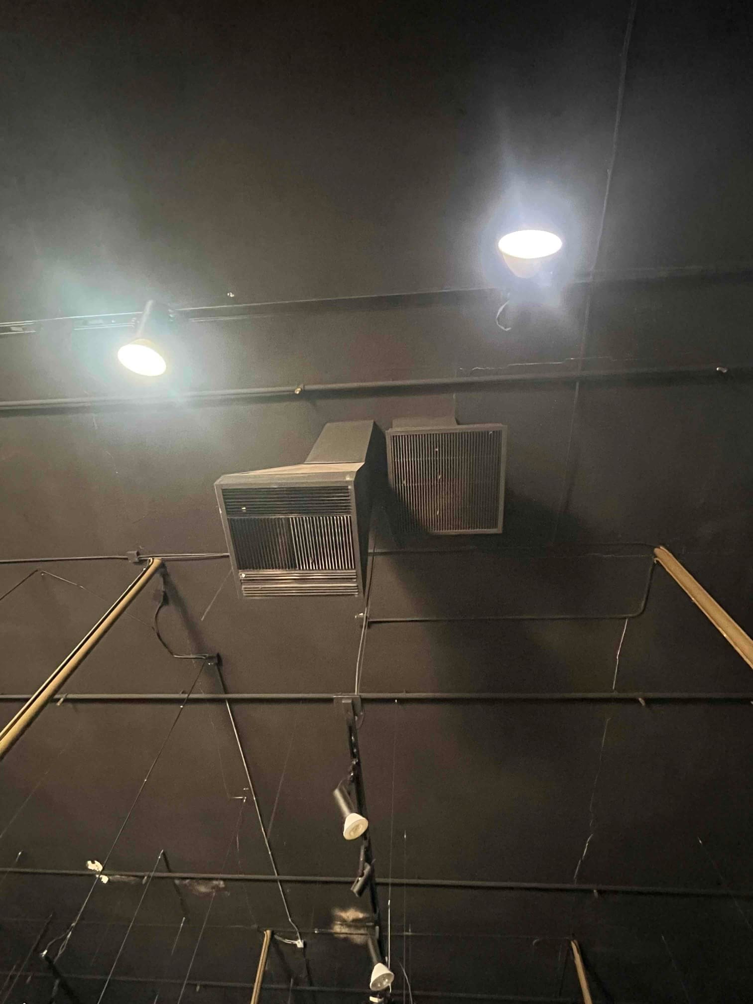 Ceiling return air grille and duct box installed among exposed conduit and lighting in a commercial space.