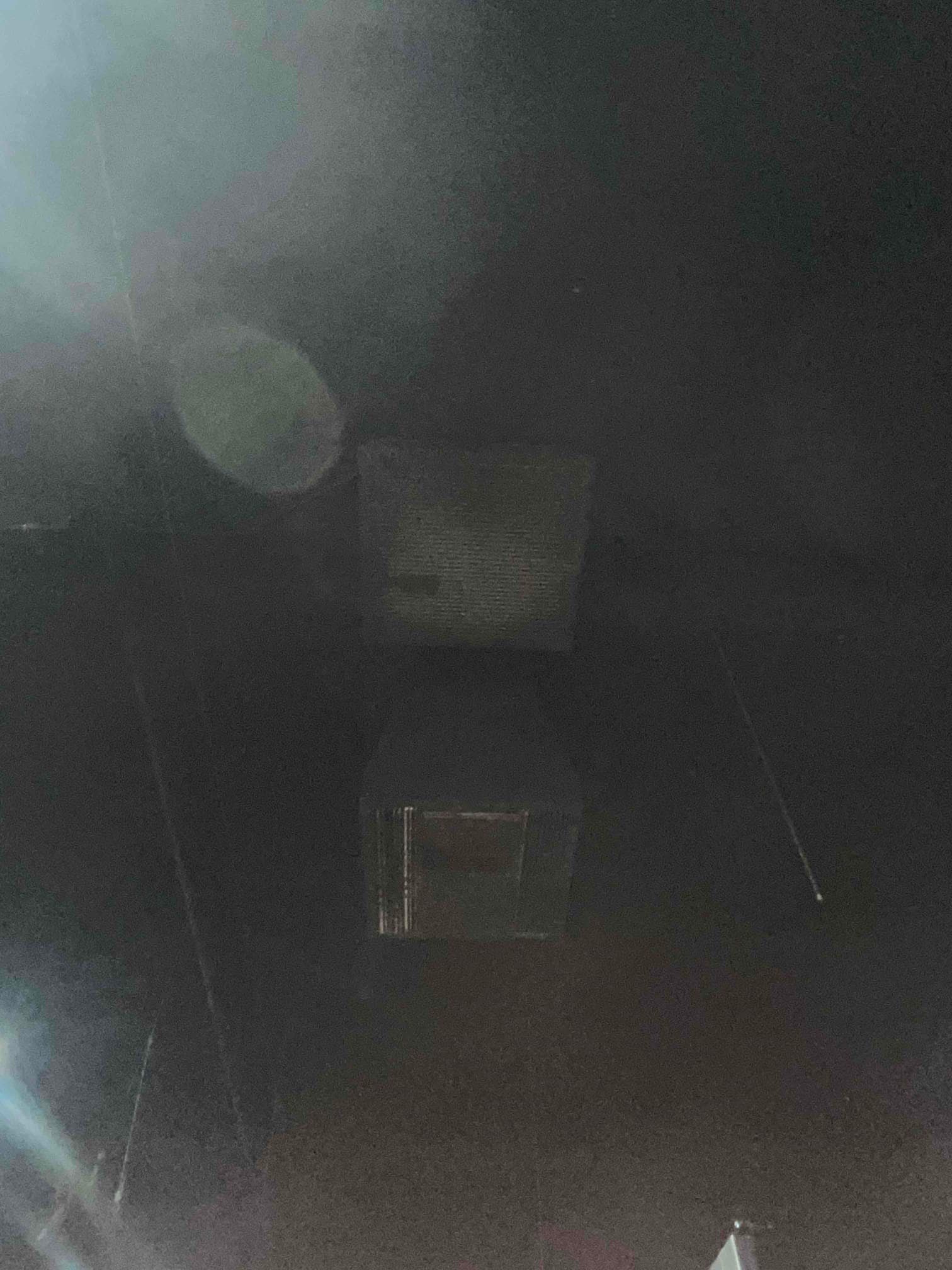 Ceiling return grille and nearby duct opening visible in a dark interior space during air conditioning repair assessment.