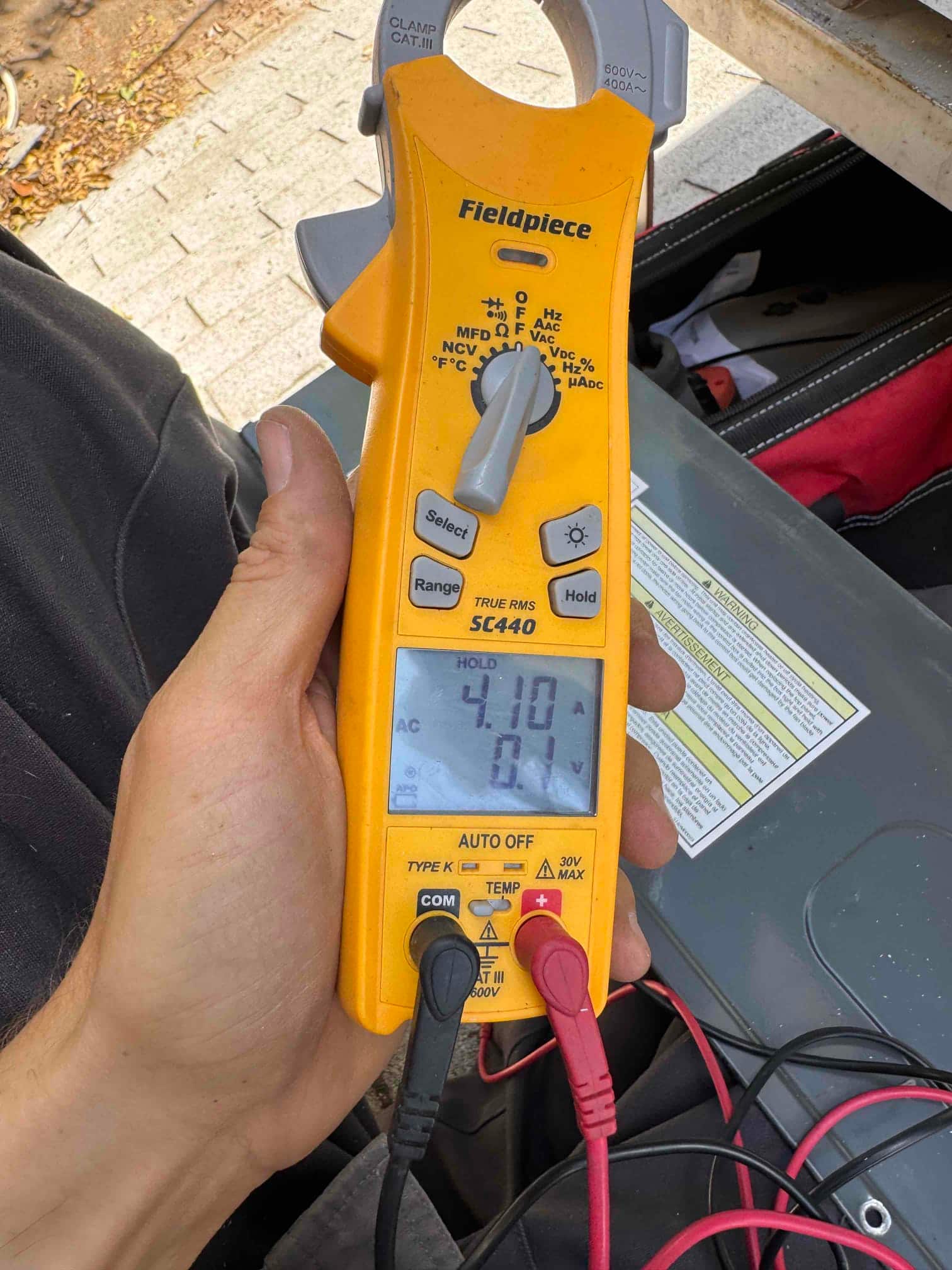 Clamp meter shows 41.0 V across the test leads at the air handler control compartment, with probes on two low-voltage terminals.