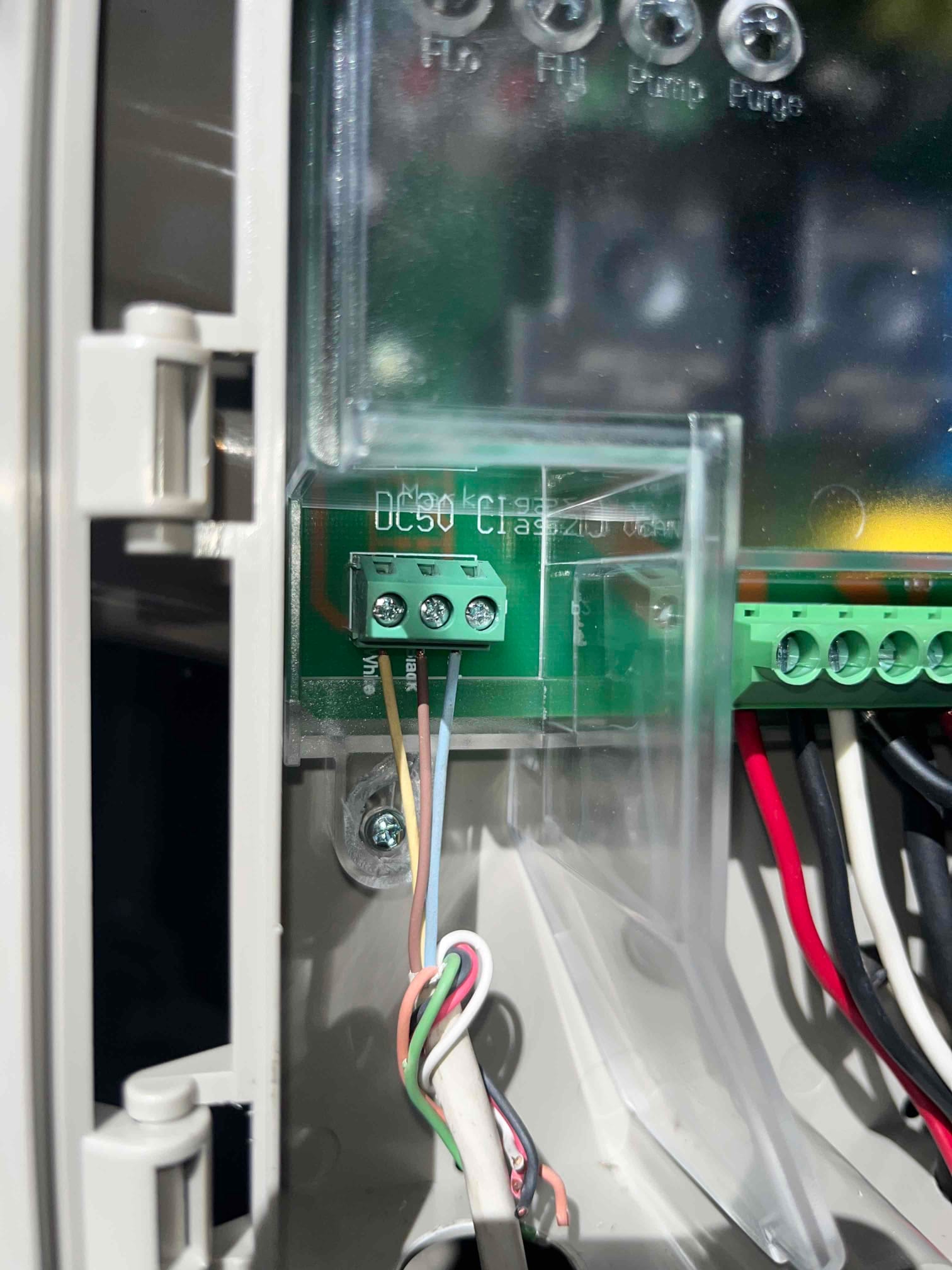 Close-up of a control board terminal block with connected low-voltage wires inside an HVAC control enclosure.