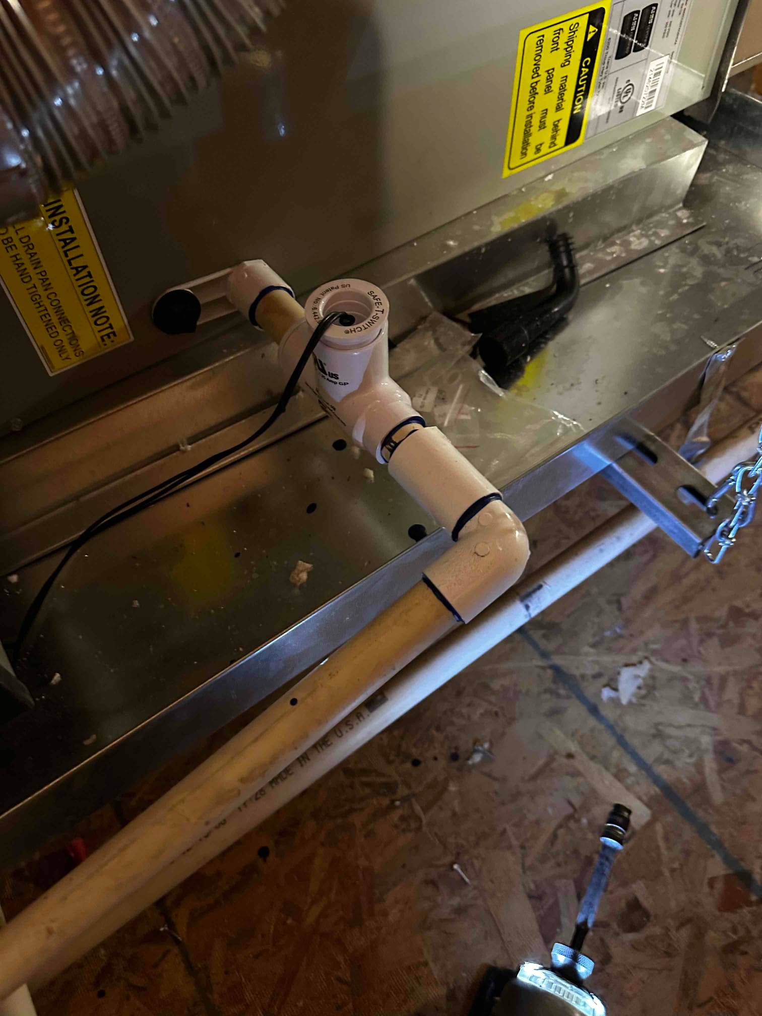 Condensate drain assembly with cleanout and safety float switch installed on the air handler drain pan.