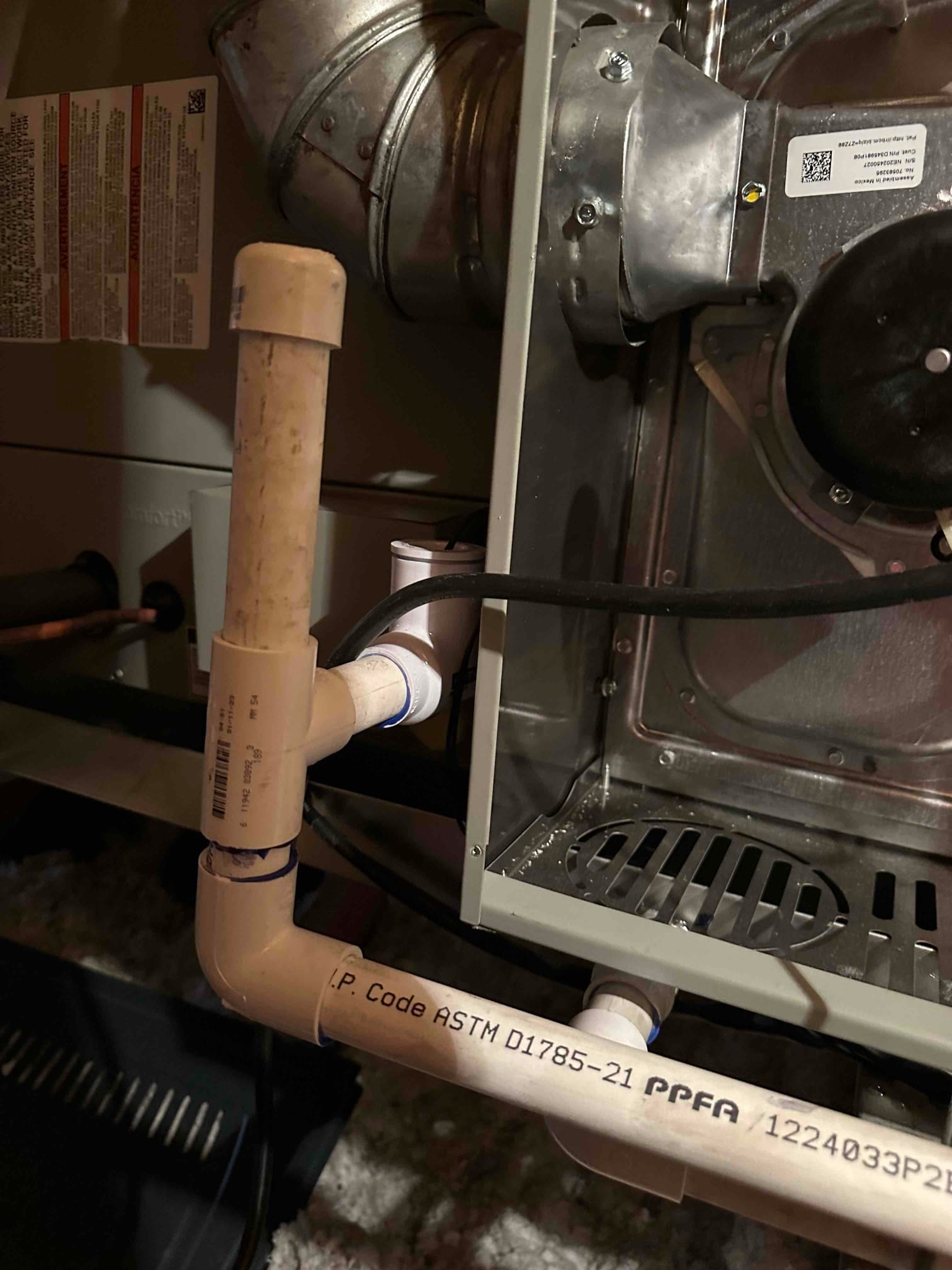 Condensate drain assembly with cleanout and trap connected to the furnace cabinet near the inducer and vent piping.