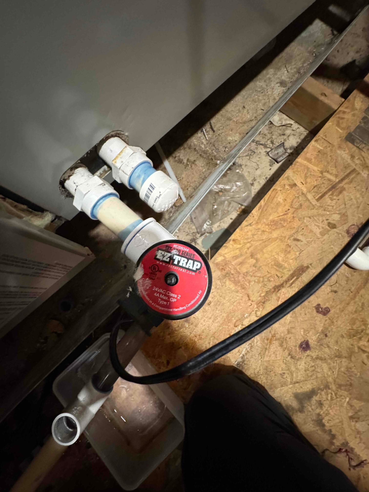Condensate drain line with EZ Trap cleanout and float switch installed near the air handler, showing PVC fittings and drain pan.
