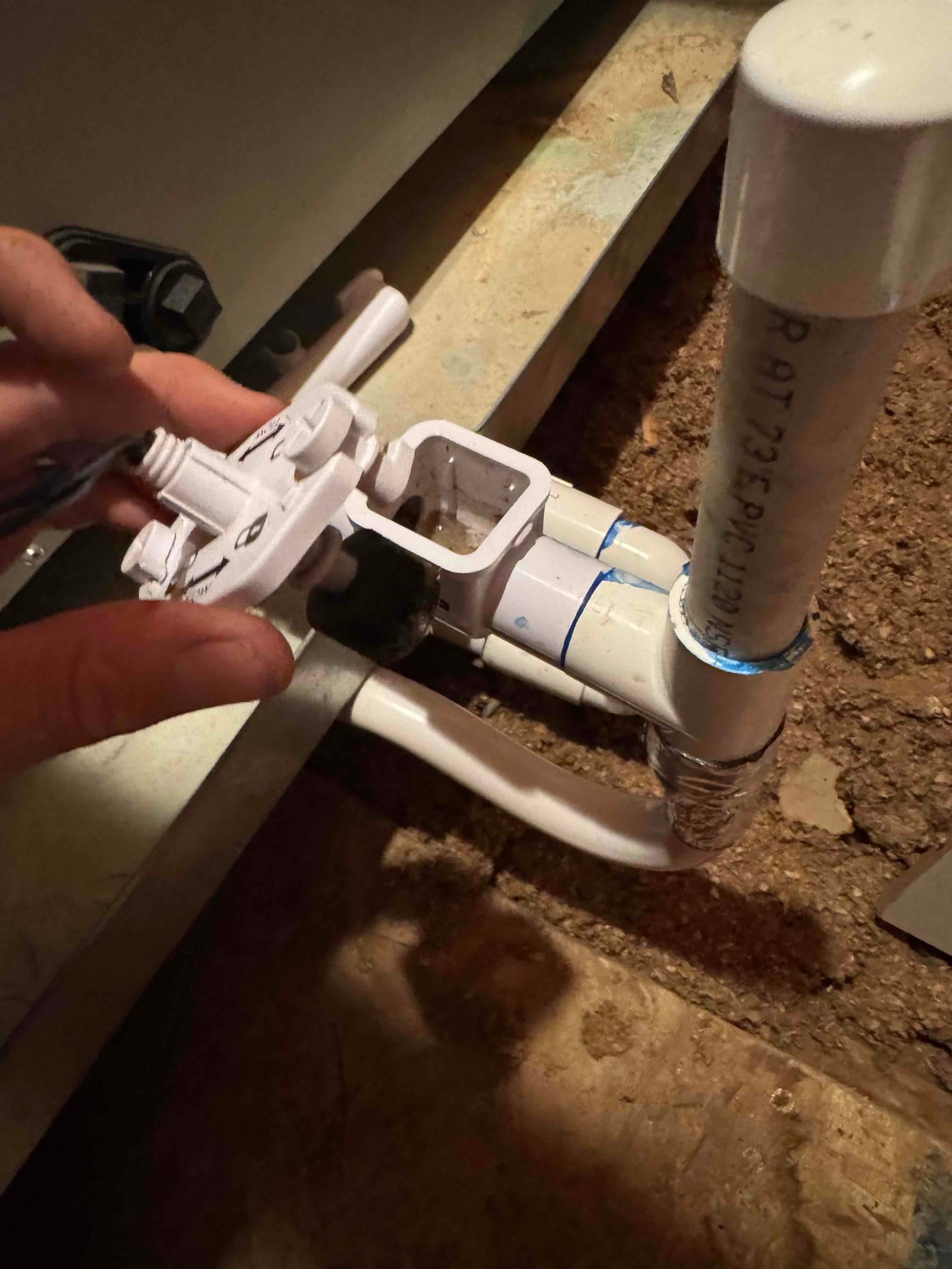 Condensate drain trap and cleanout assembly opened for cleaning, showing PVC fittings and accessible cleanout cap near the air handler.