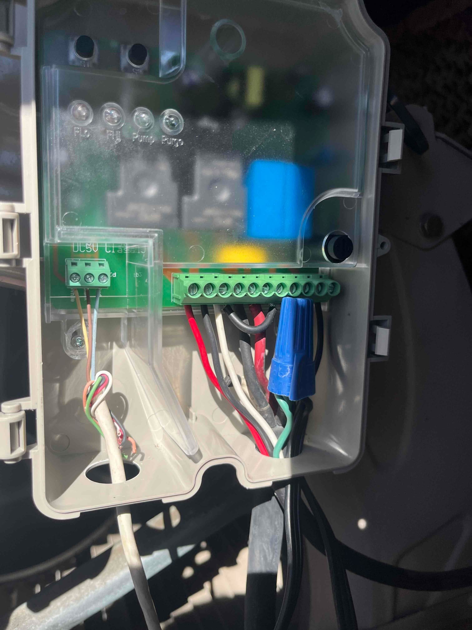 Control box interior showing low-voltage and line-voltage wiring connections, wire nut splice, and circuit board terminals inside the cooler.