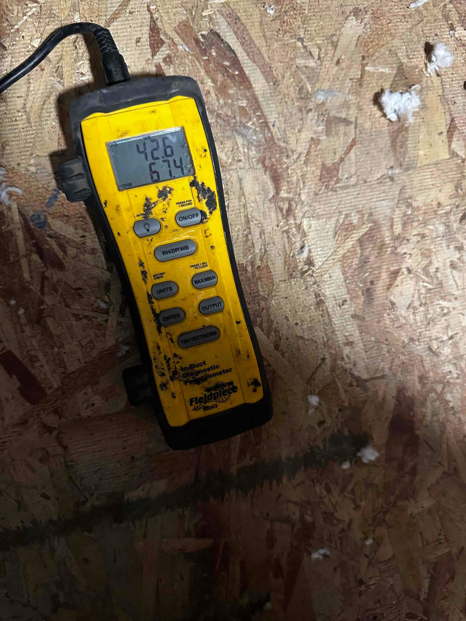 Digital in-duct thermometer displays 42.6°F and 67.4°F during air temperature measurements for commissioning.