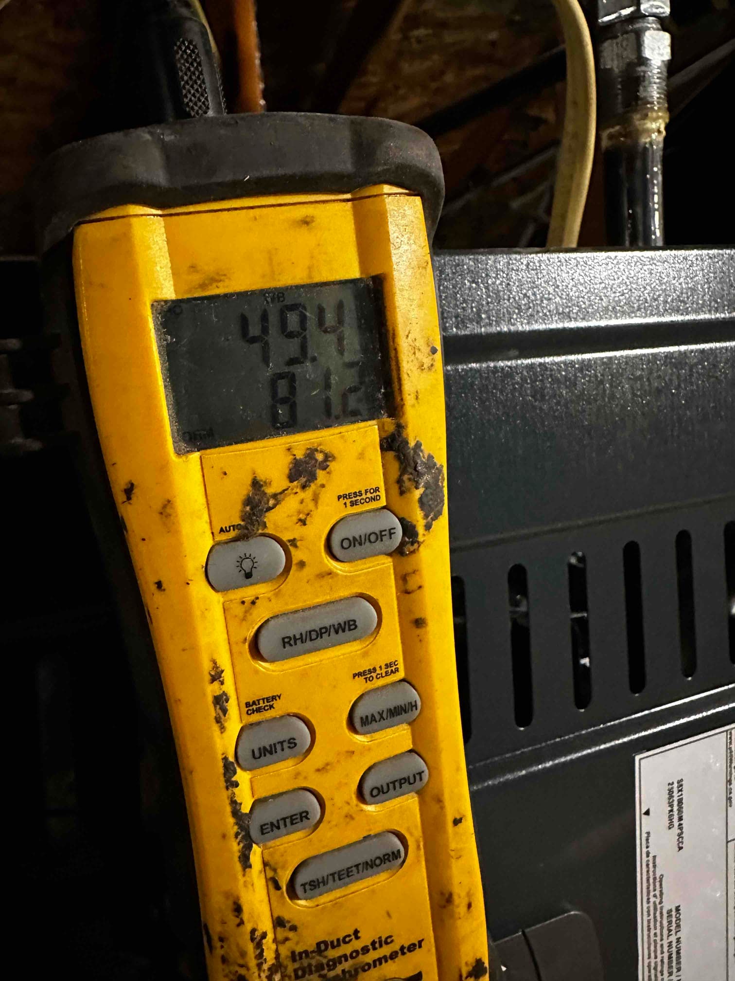 Digital in-duct thermometer displays 49.4°F, documenting cold supply air temperature after the evaporator during system commissioning.