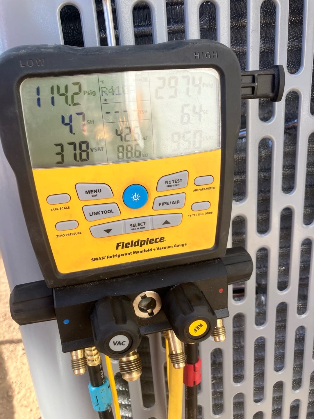 Digital manifold connected to the condenser shows operating refrigerant pressures during system commissioning.