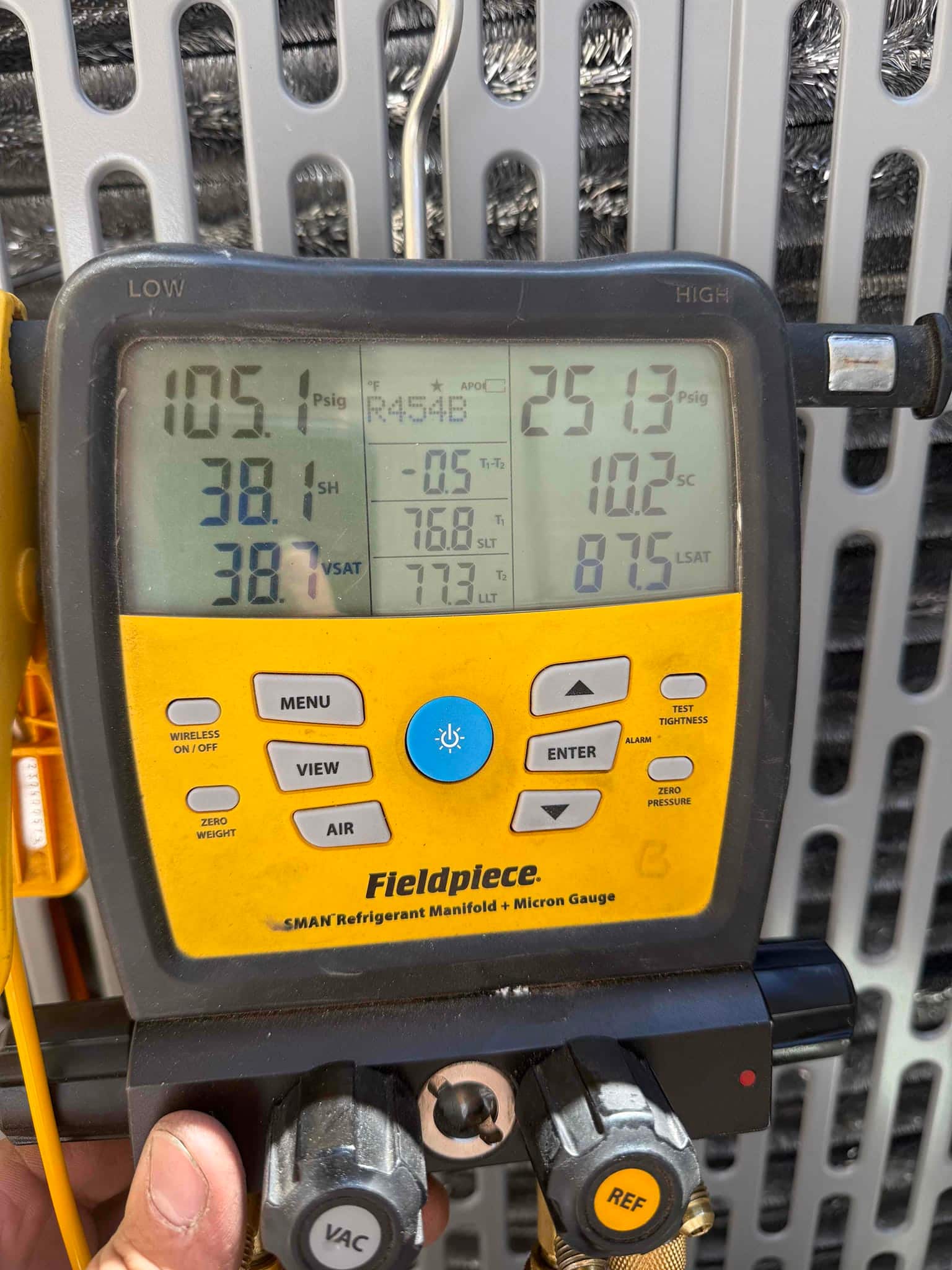 Digital manifold connected to the outdoor unit shows operating pressures and temperatures during system commissioning using R-454B refrigerant.