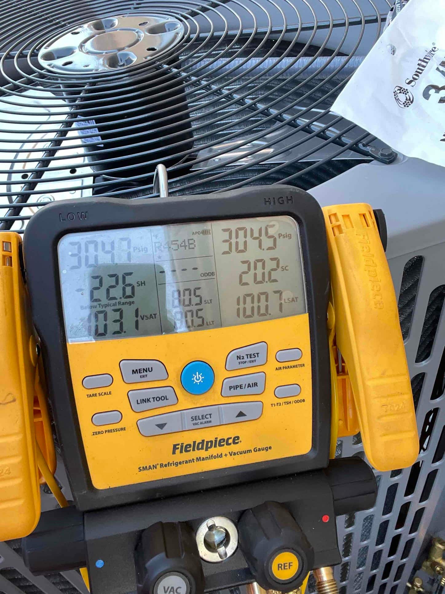 Digital manifold on the outdoor unit shows operating pressures and temperatures while commissioning the new air conditioning system.